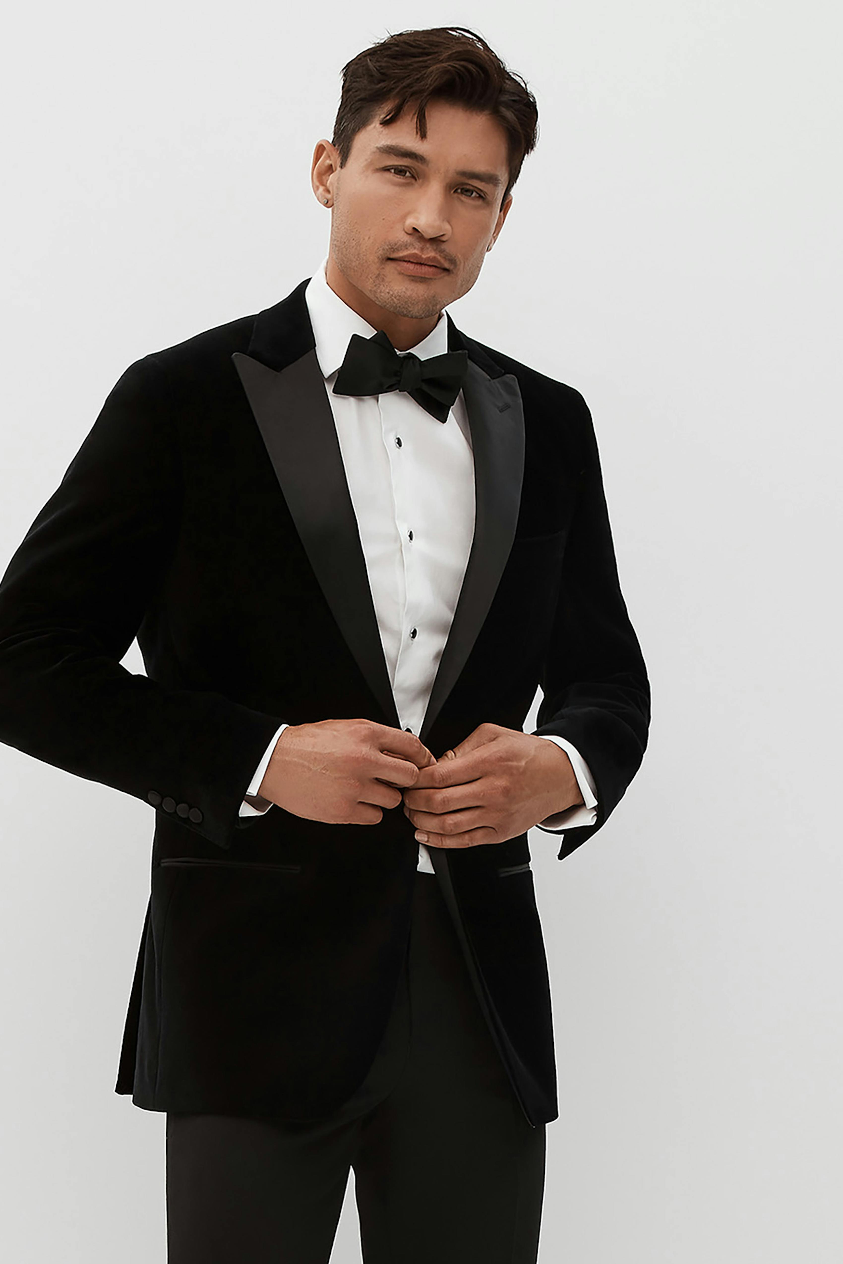 Black velvet tuxedo with peak lapels as a black tie winter wedding outfit for men