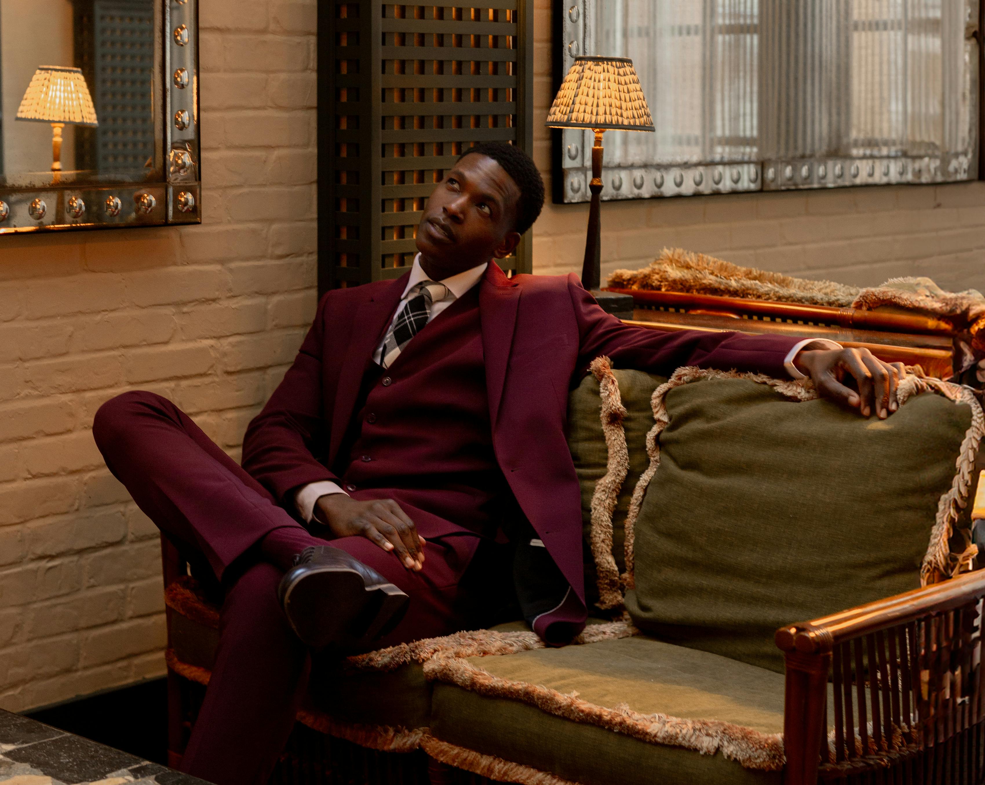 Man wearing dark burgundy suit with plaid tie as a guest at vintage winter wedding