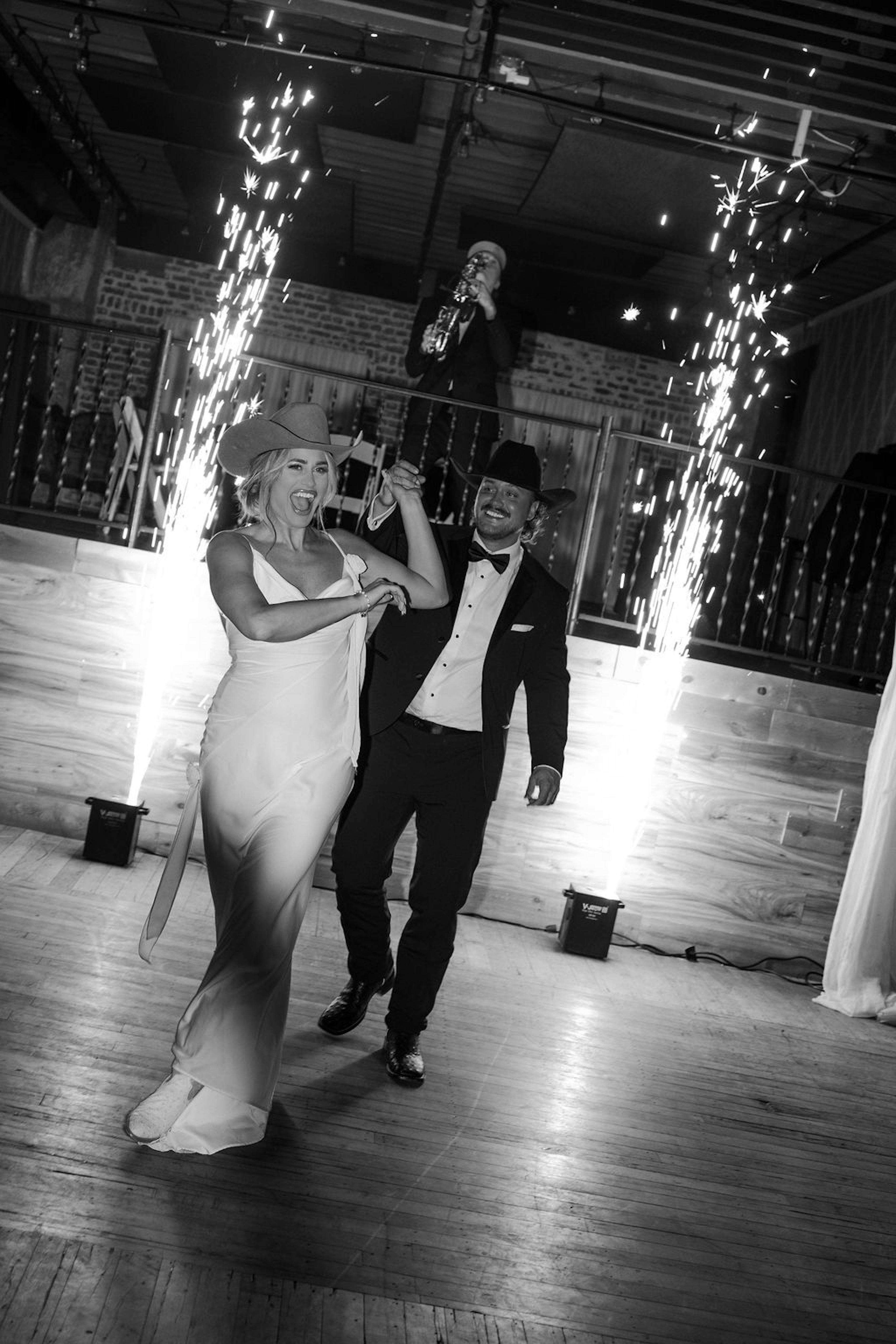 bride and groom wearing cowboy hats for wedding reception sparkler entrance
