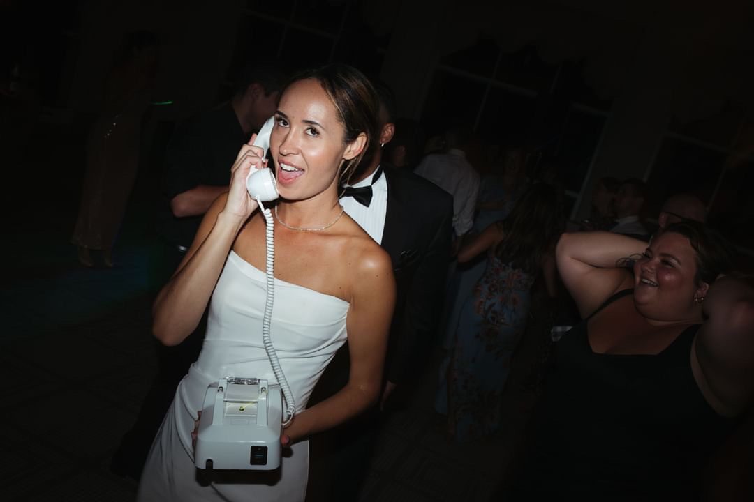 Bride holding vintage rotary phone to leave a voicemail guestbook message