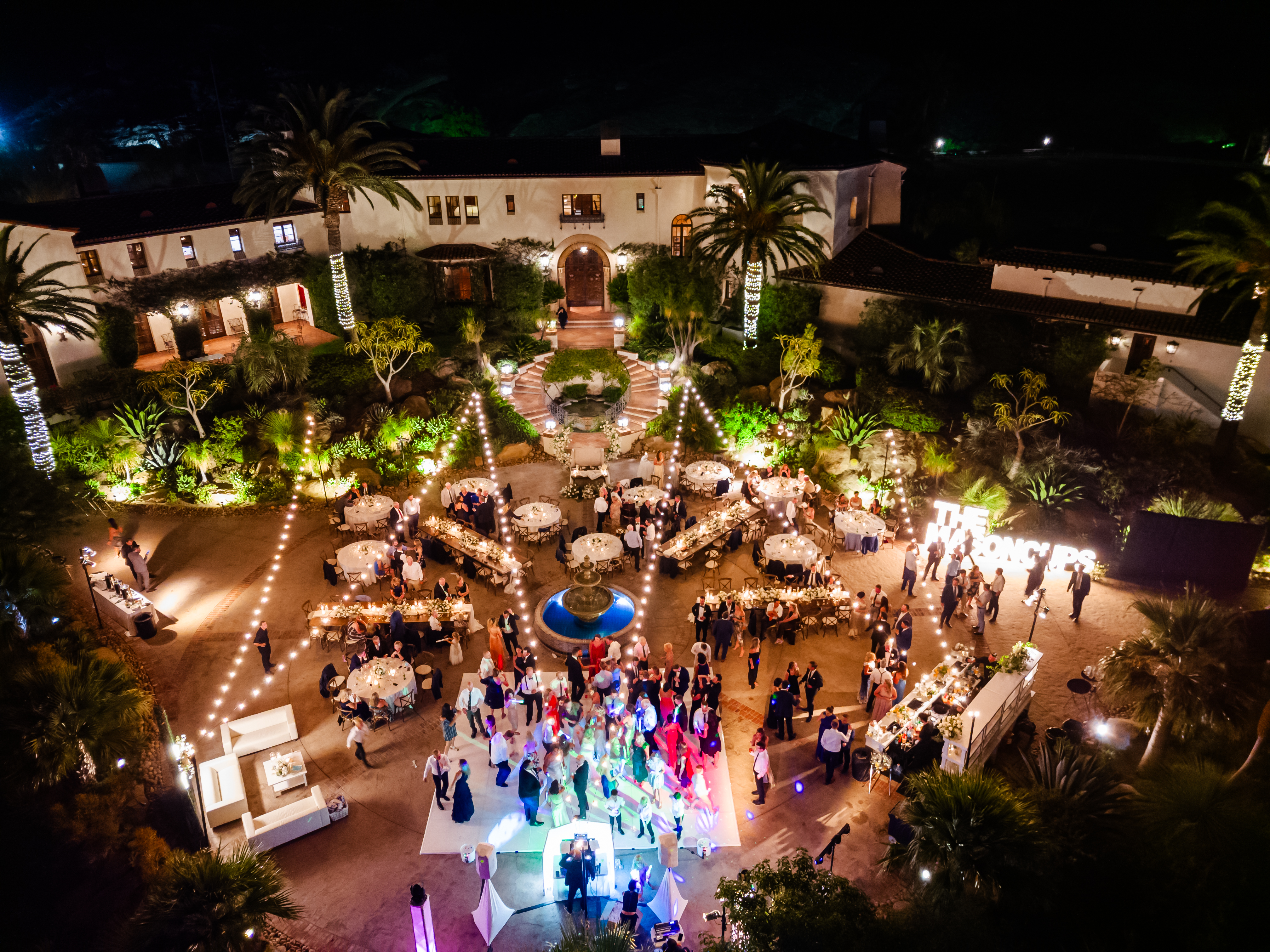 Birds eye view of tropical outdoor wedding reception at night with guests dancing