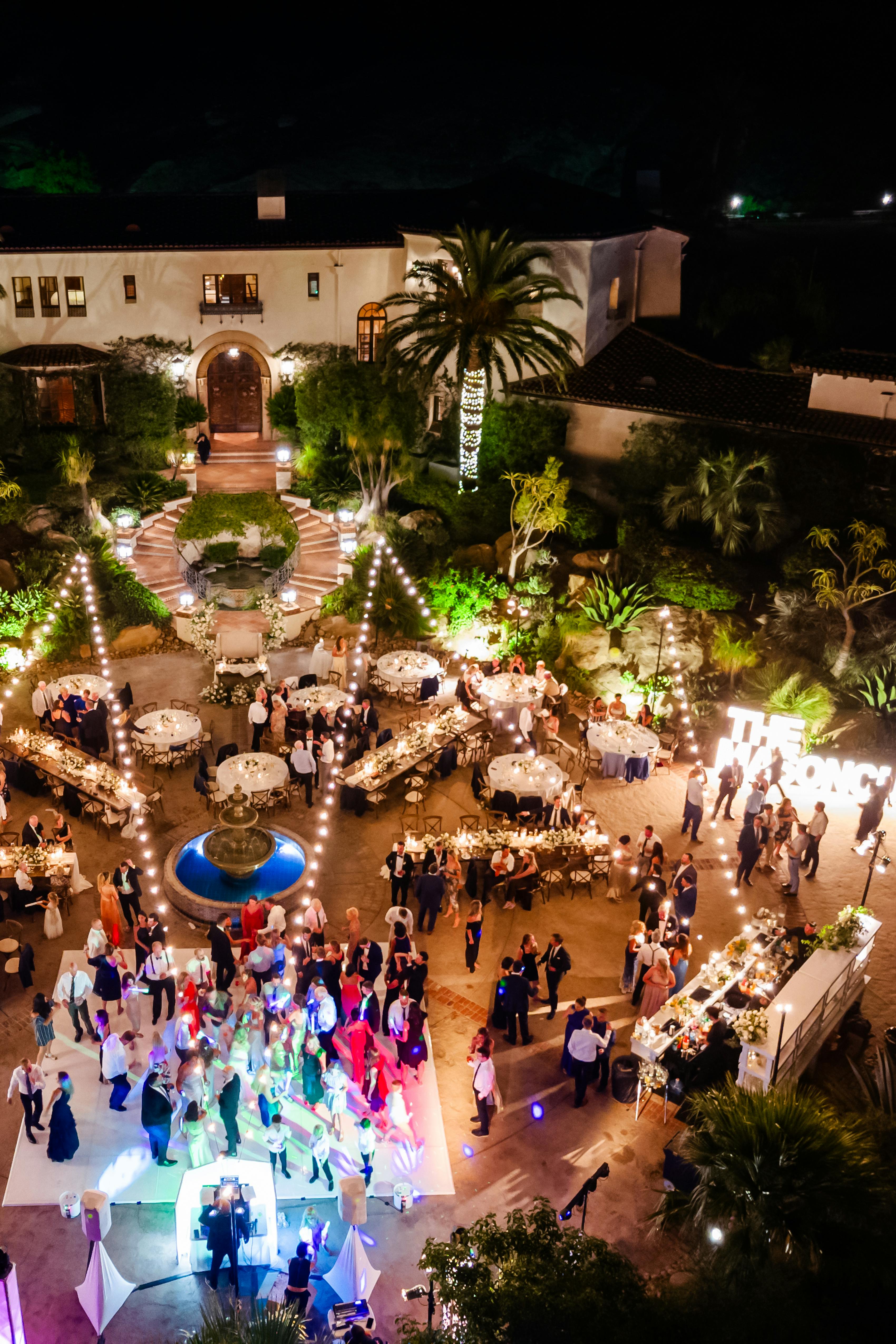 Birds eye view of tropical outdoor wedding reception at night with guests dancing