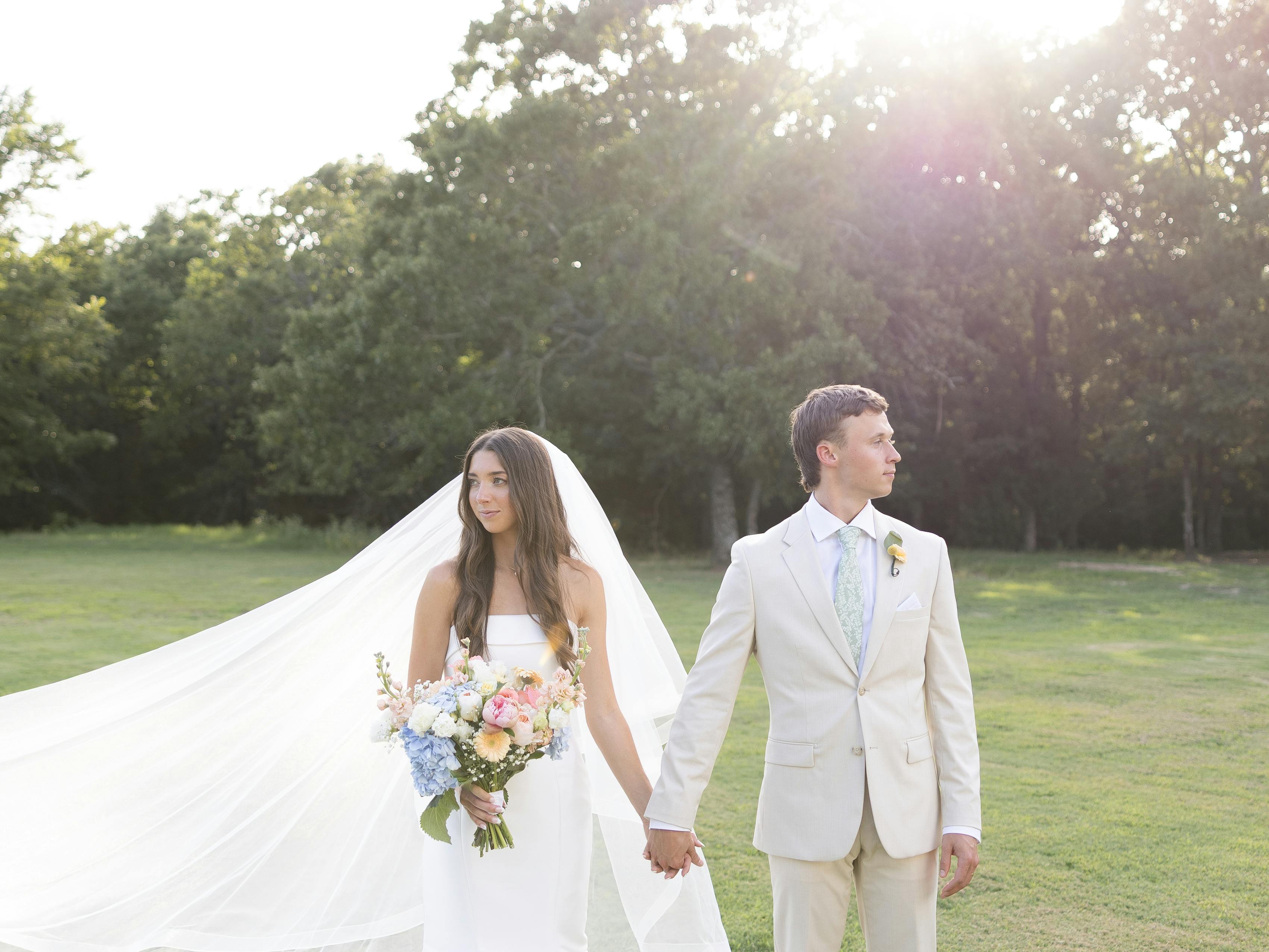 Wedding first touch with classic bridal gown, tan groom's suit, and pastel tie and bouquet
