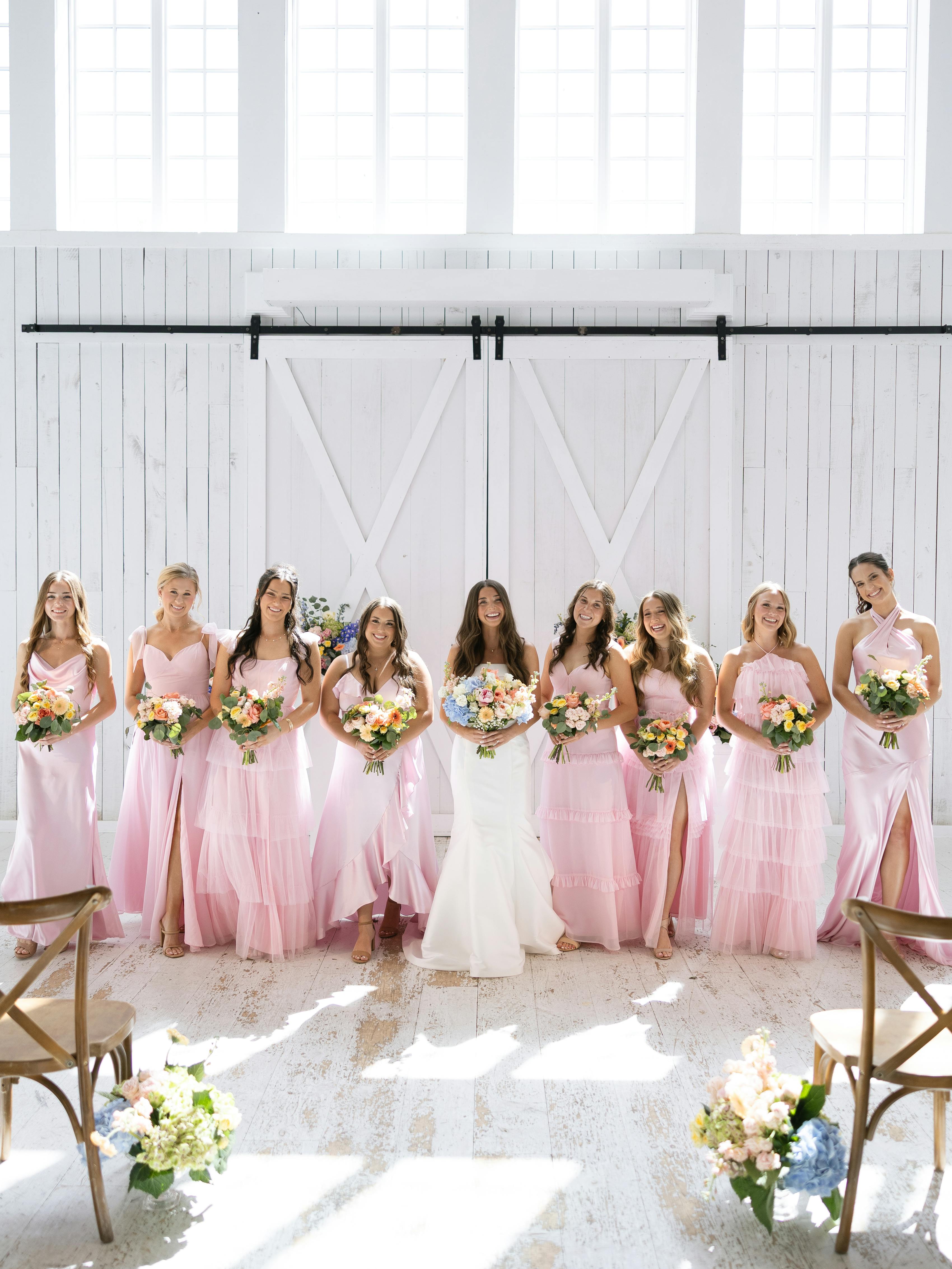 Bride with bridesmaids wearing light pink dresses at barn wedding