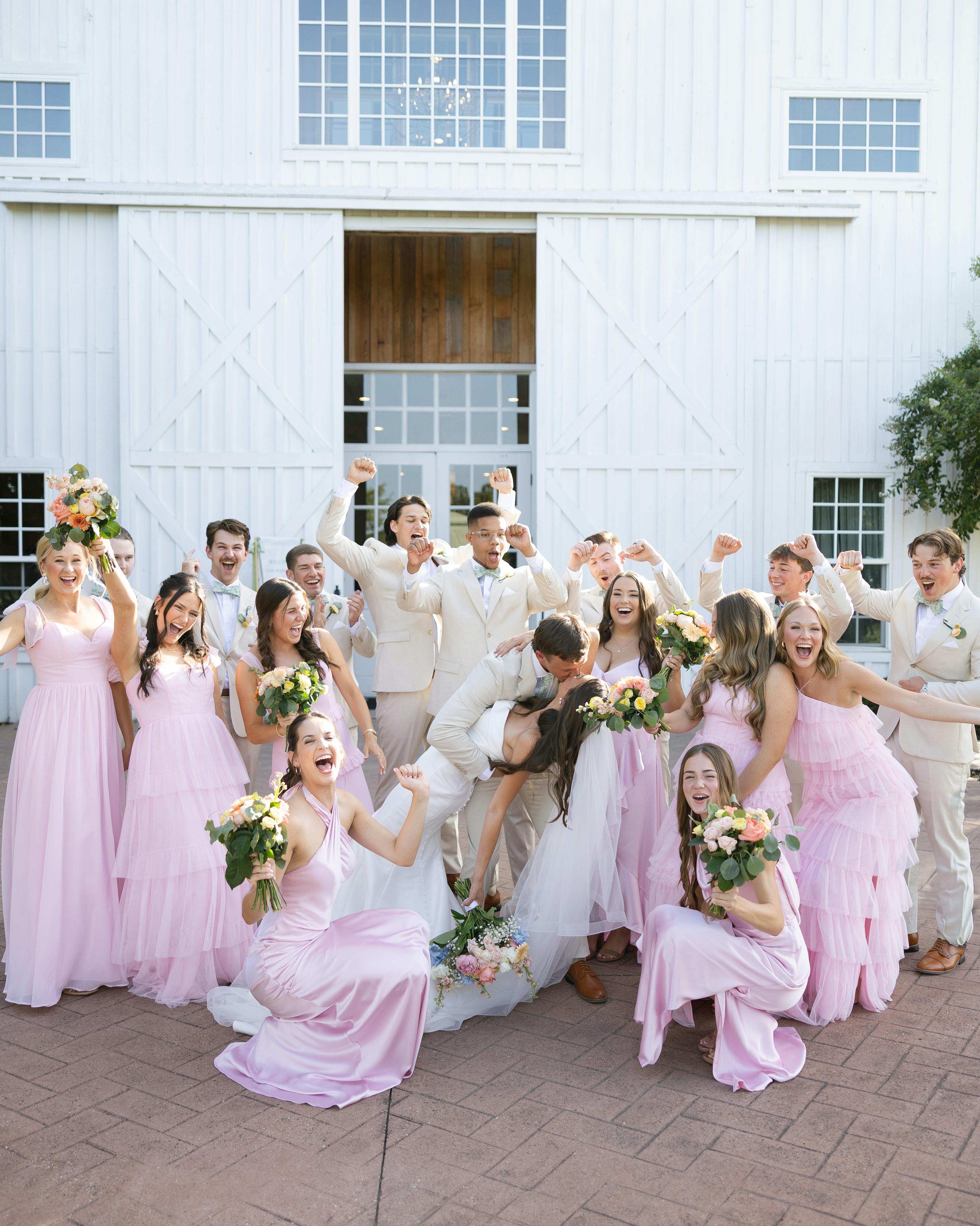 Tan and light pink bridal party and groomsmen with bride and groom at barn wedding