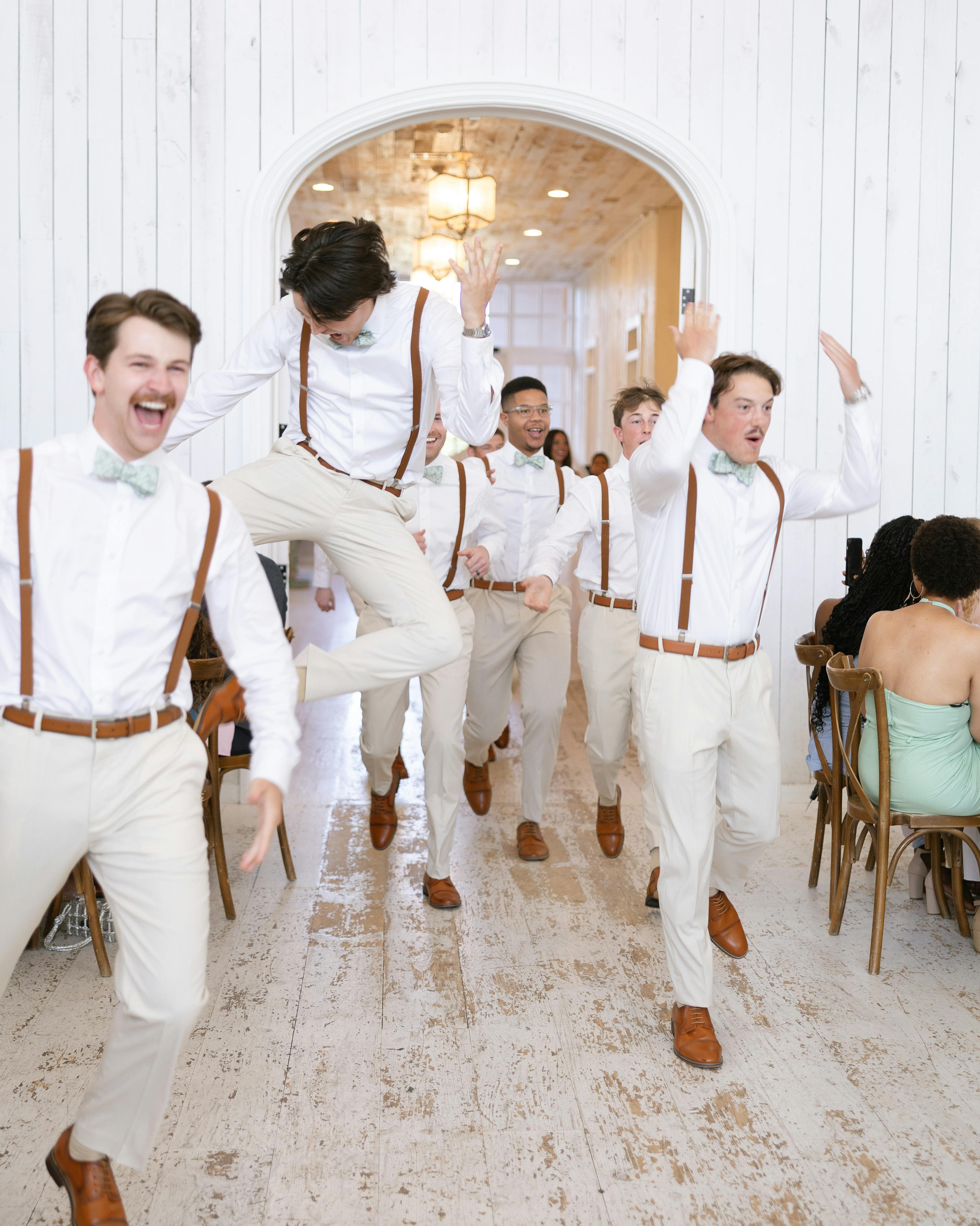 Groomsmen entering wedding reception wearing tan suit pants and brown suspenders