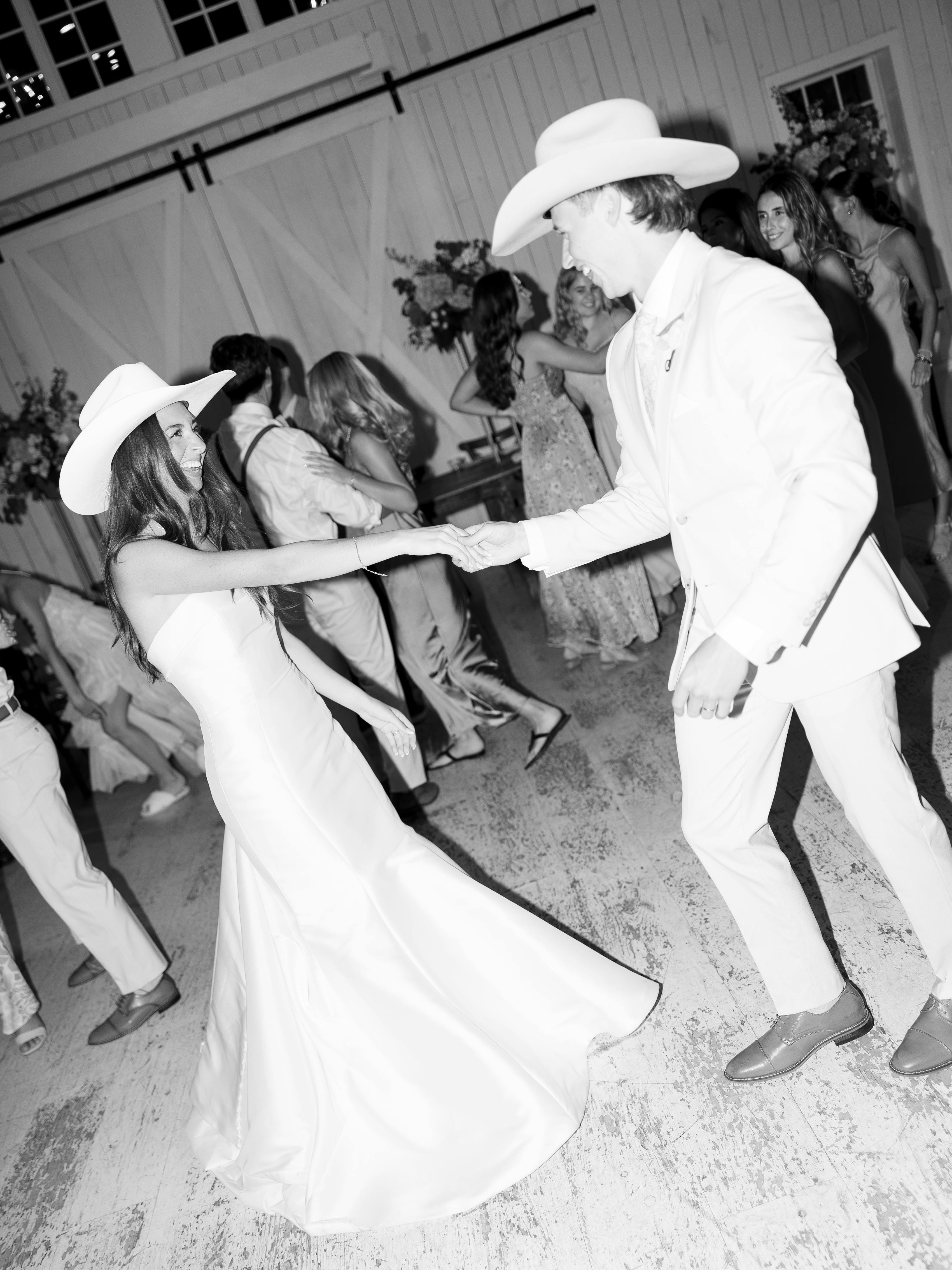 Bride and groom wearing cowboy hats dancing at wedding reception