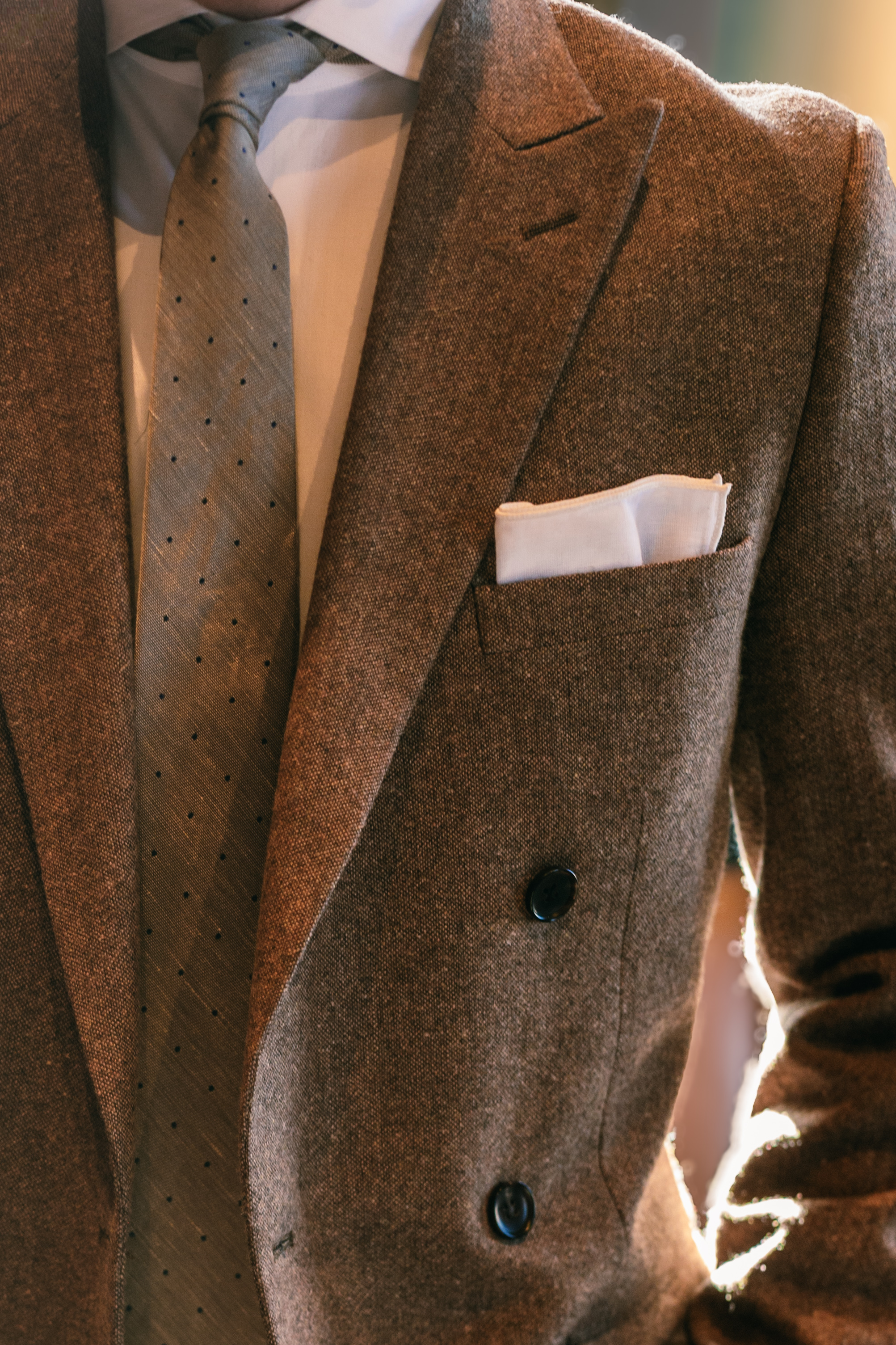 Closeup of brown tweed double breasted men's suit jacket with matching brown tie
