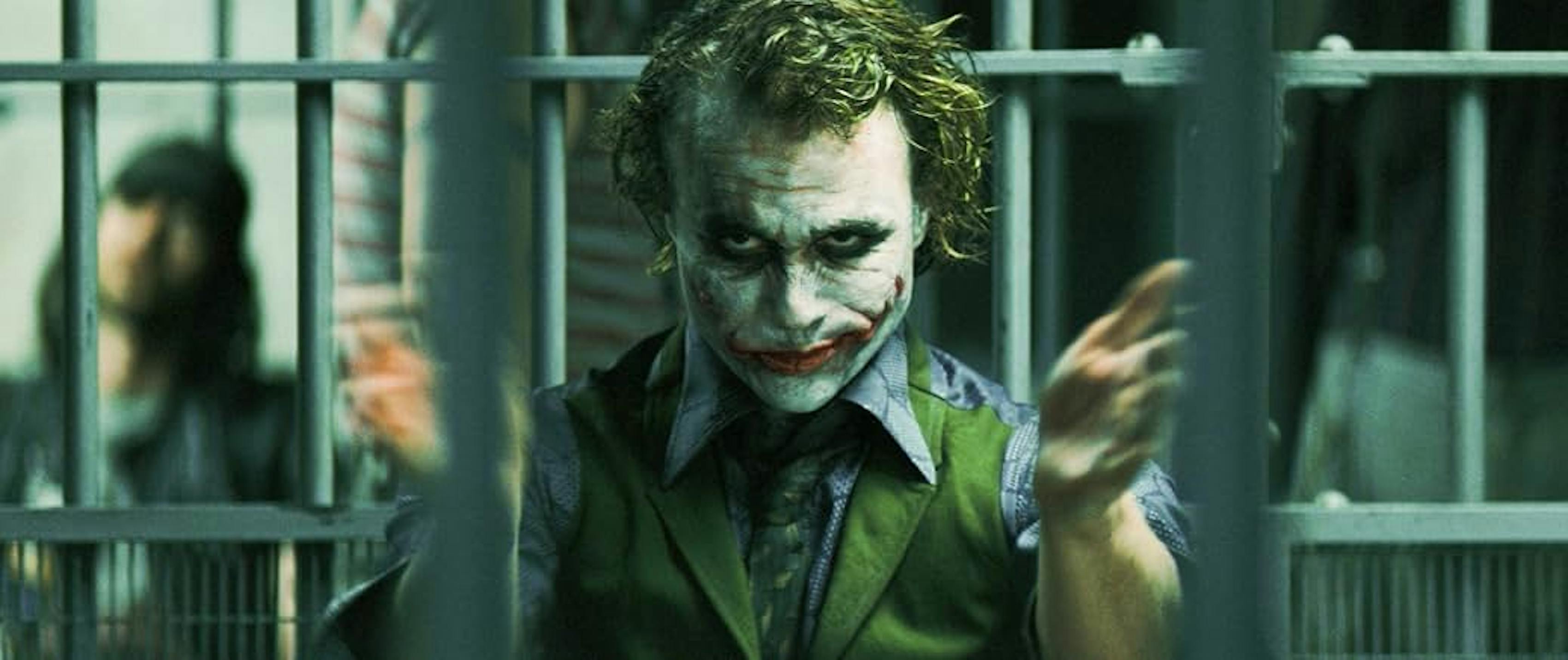 Heath Ledger as The Joker in green suit vest behind bars