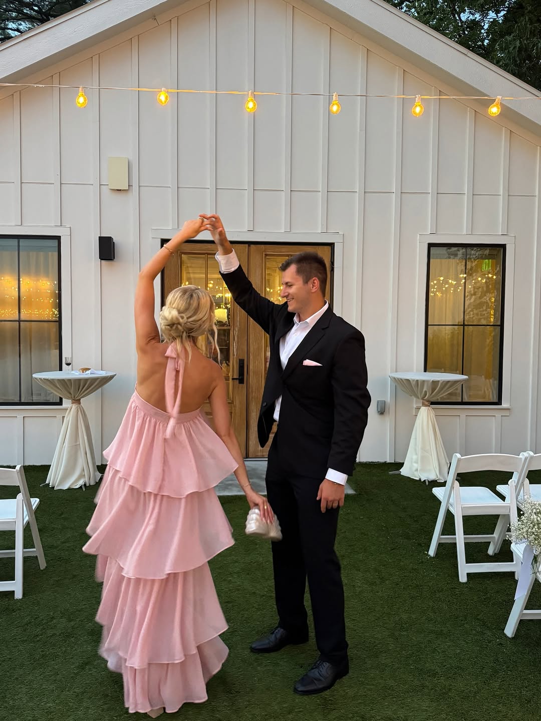Couple wearing formal rehearsal dinner outfits with pink ruffle halter dress and black suit