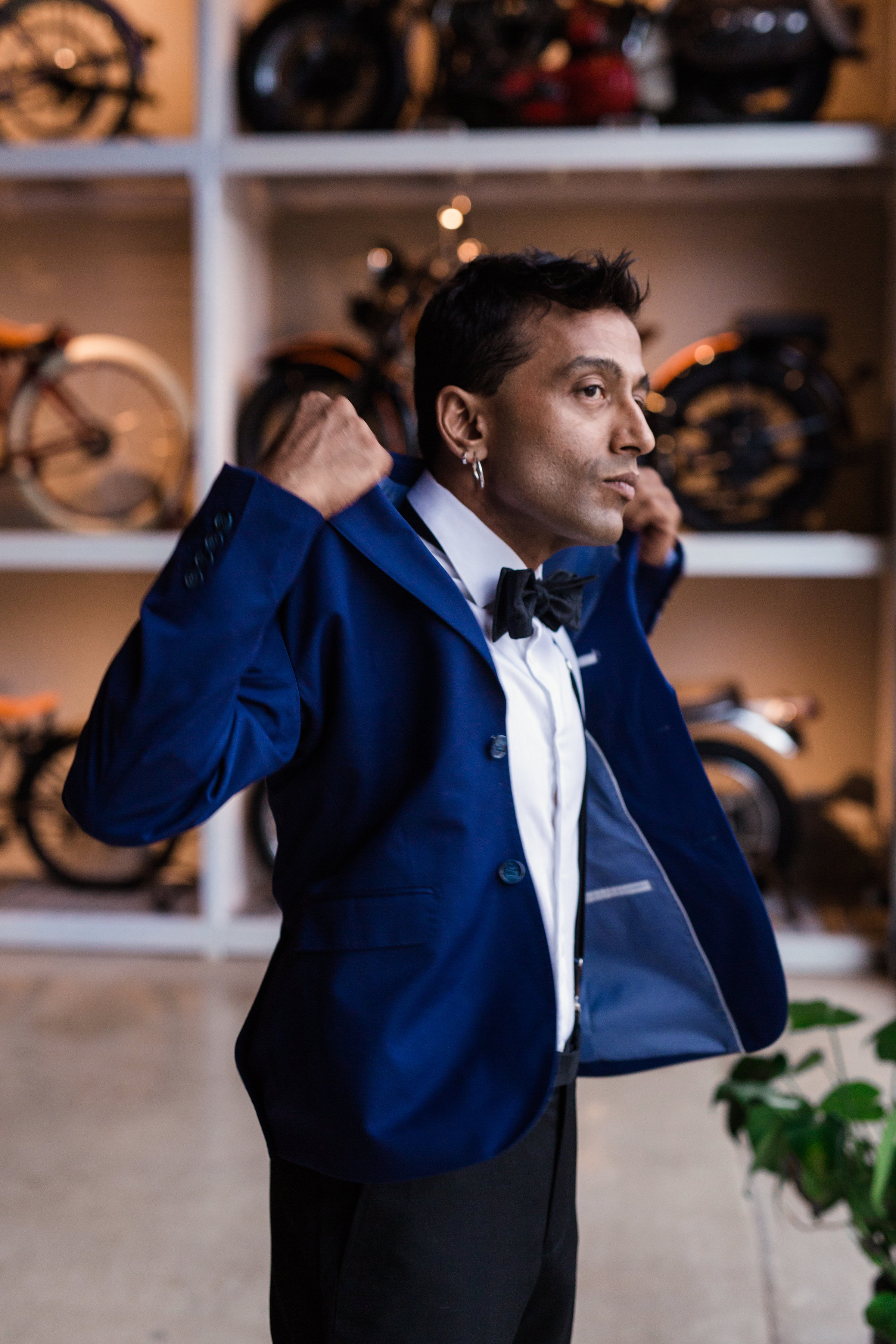 Man putting on navy blue tuxedo jacket at wedding