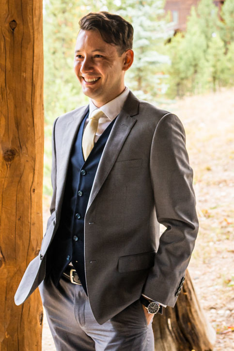 Groom wearing light grey suit with navy blue vest at wedding