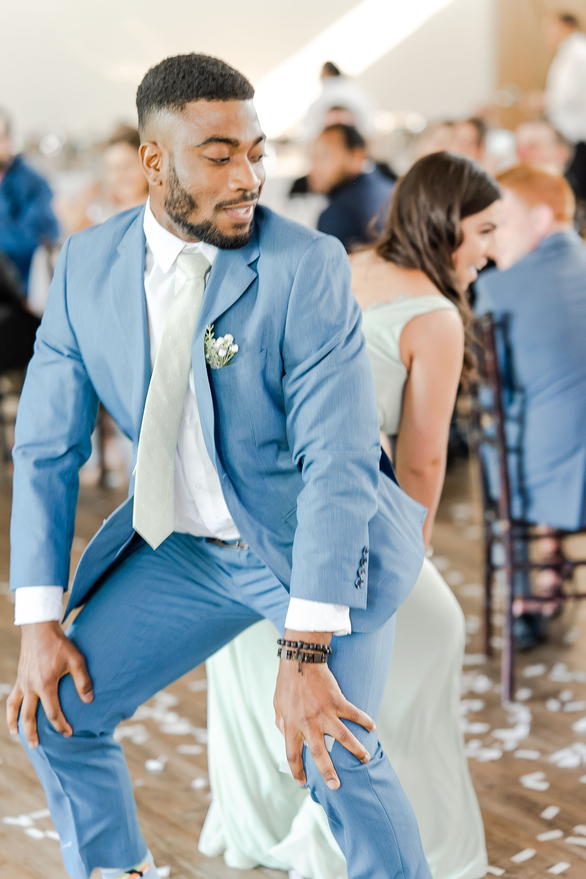Groom dancing in light blue suit at wedding party