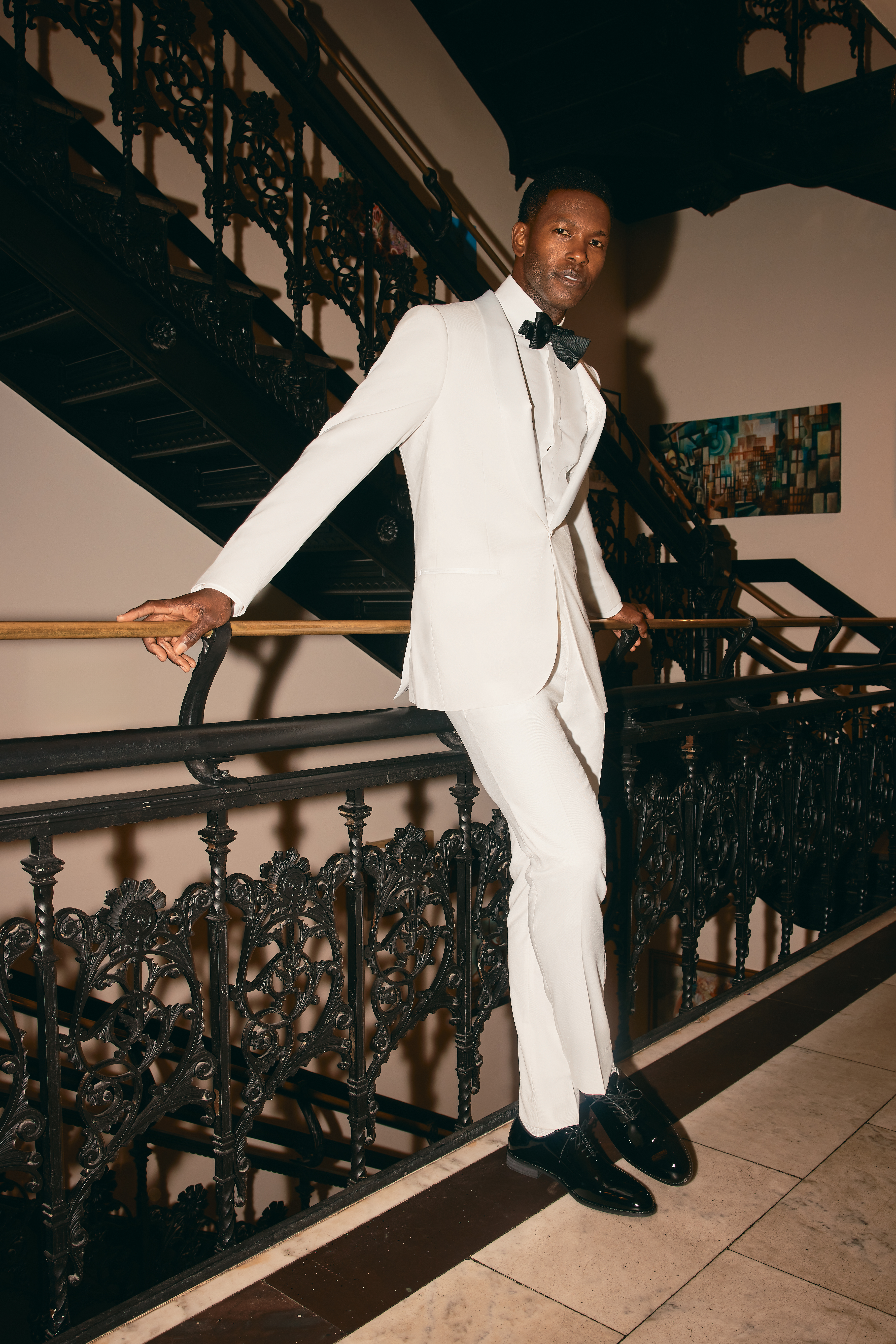 Groom wearing monochrome white tuxedo with bow tie for wedding reception second outfit