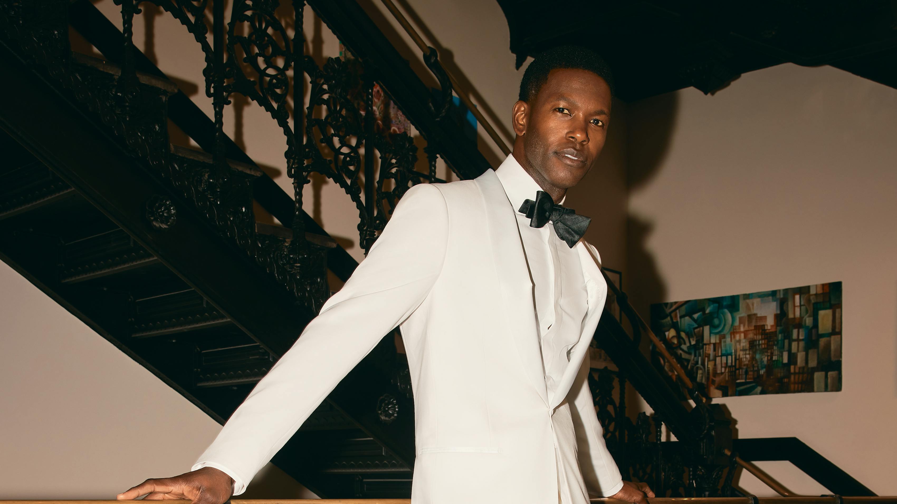 Groom wearing monochrome white tuxedo with bow tie for wedding reception second outfit