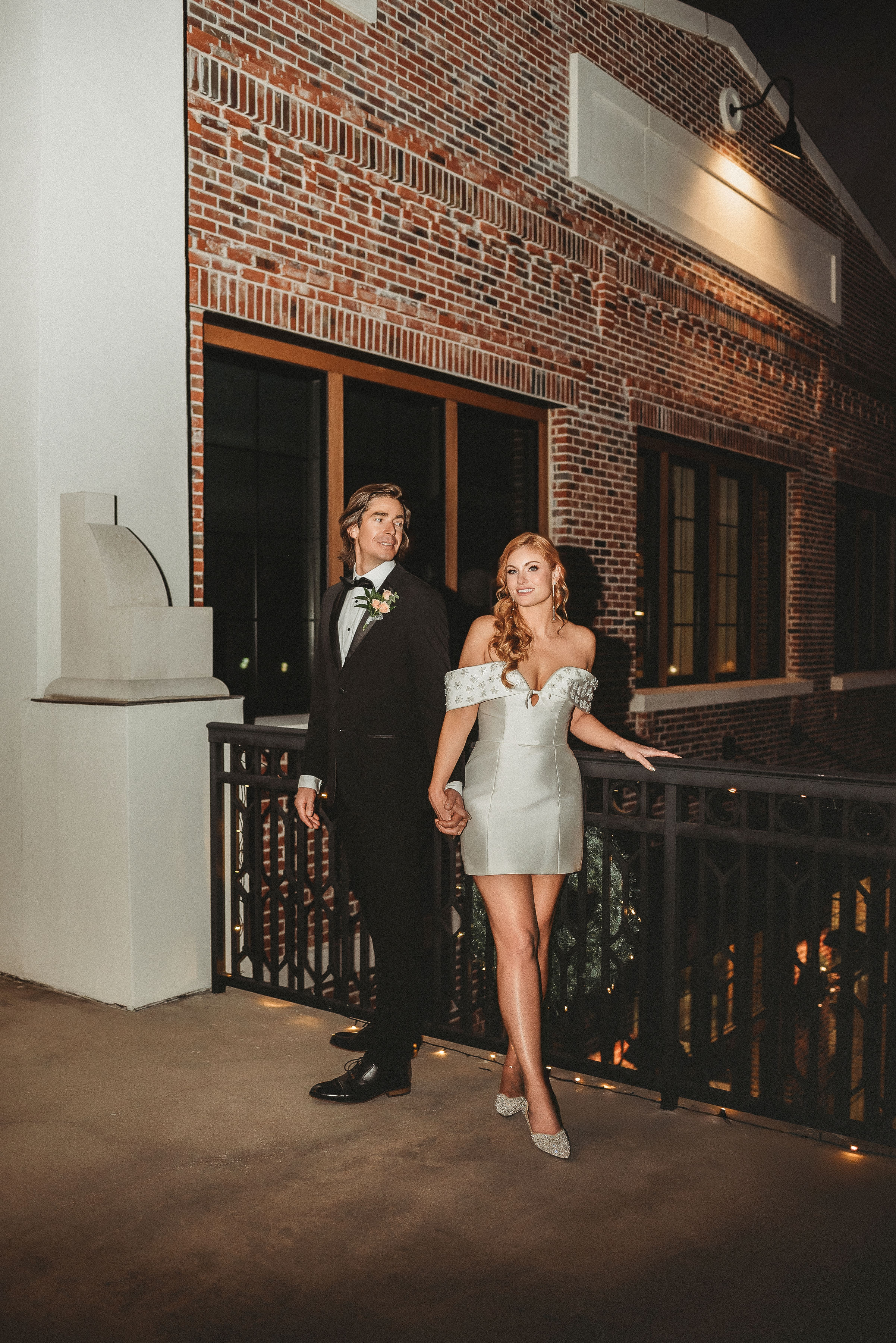 Fancy rehearsal dinner outfits with short white dress for bride and black tuxedo for groom