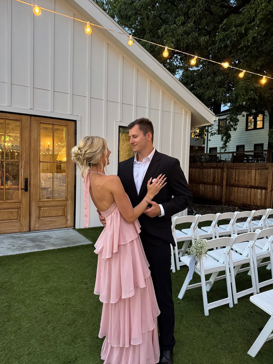 Bride and groom wearing pink ruffle rehearsal dinner dress and classic black suit