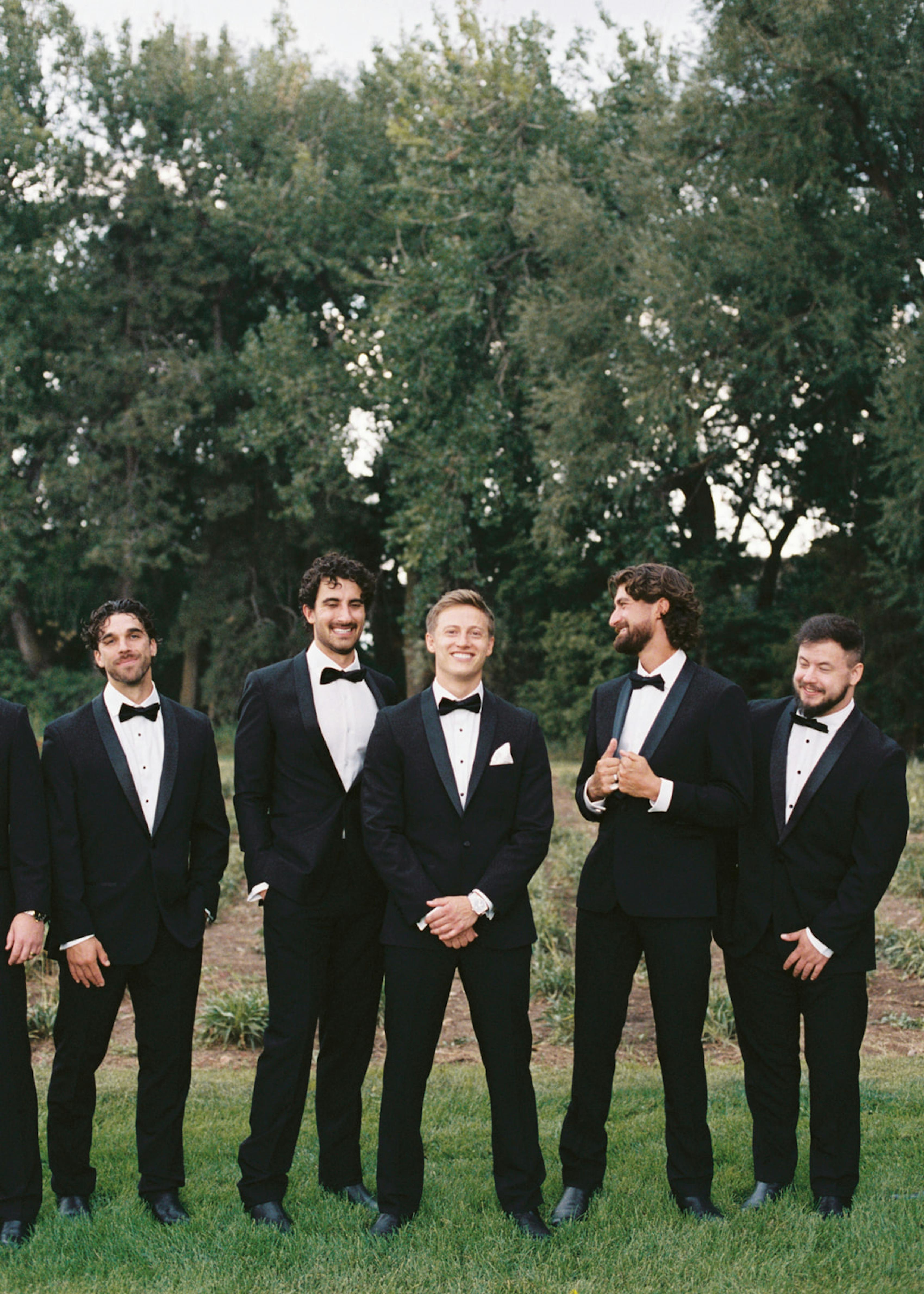 Black tie groomsmen wearing shawl lapel black tuxedos at outdoor wedding