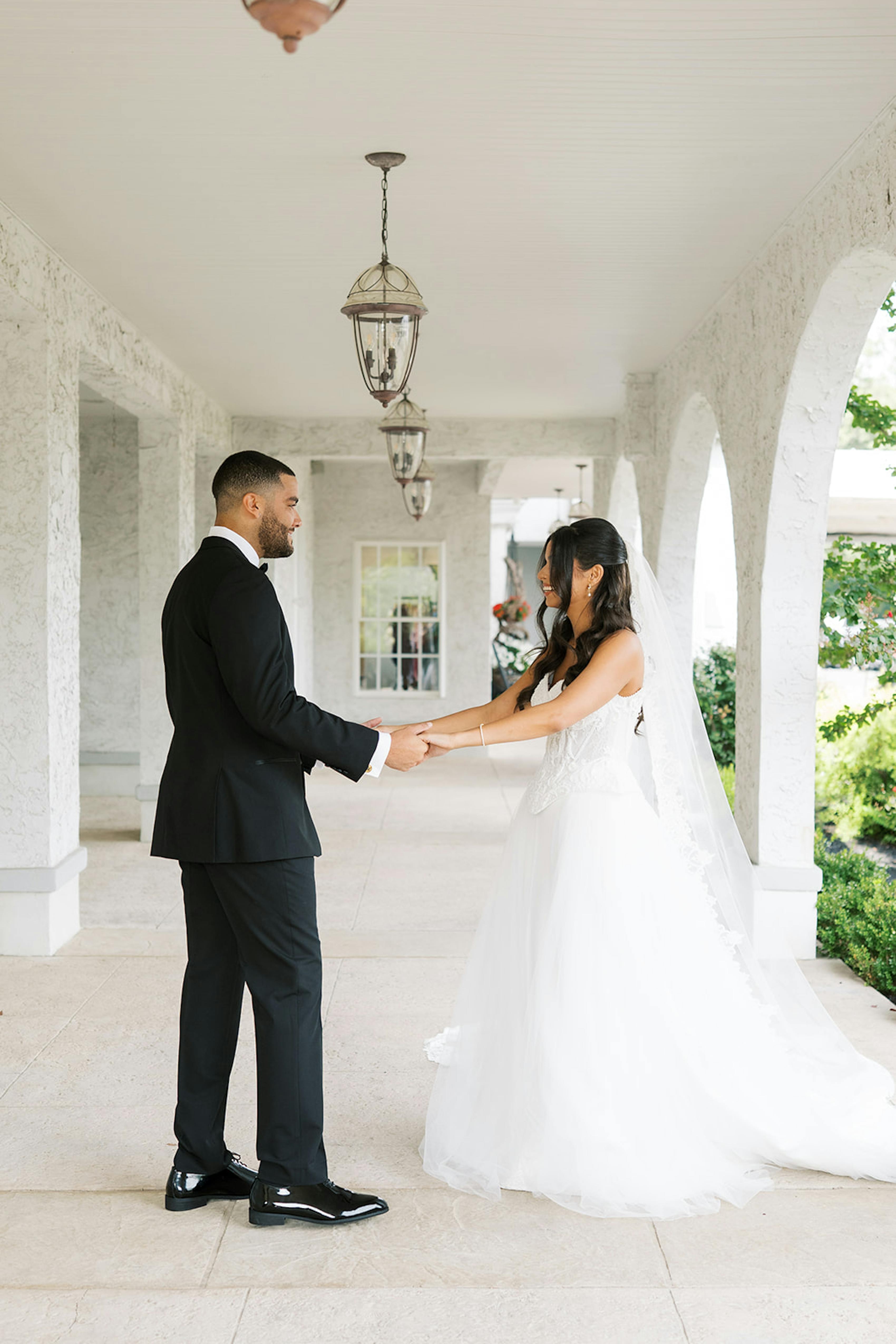 First look at black tie outdoor wedding with black groom's tuxedo and tulle bridal gown