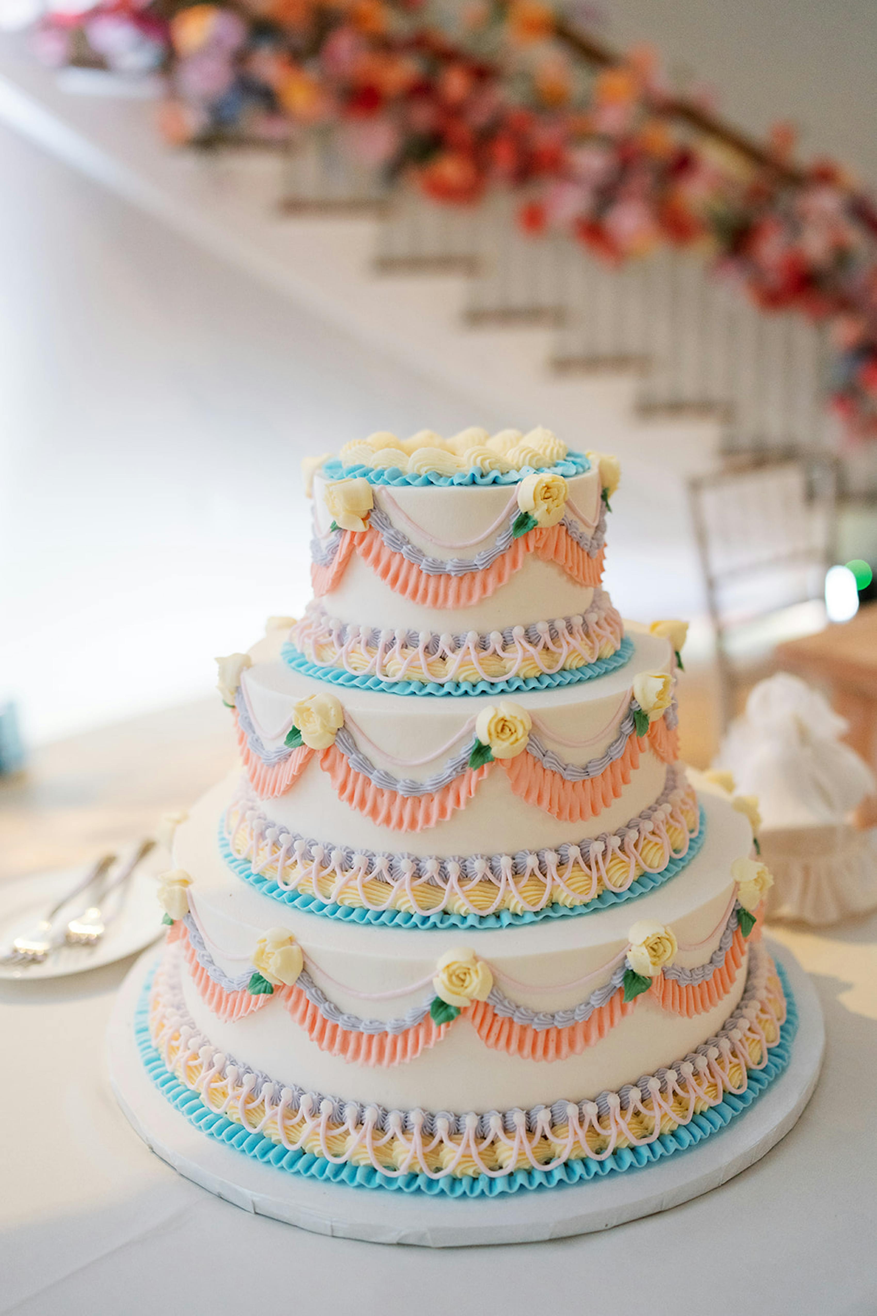Colorful 3 tier wedding cake with pastel piping and classic floral decorations