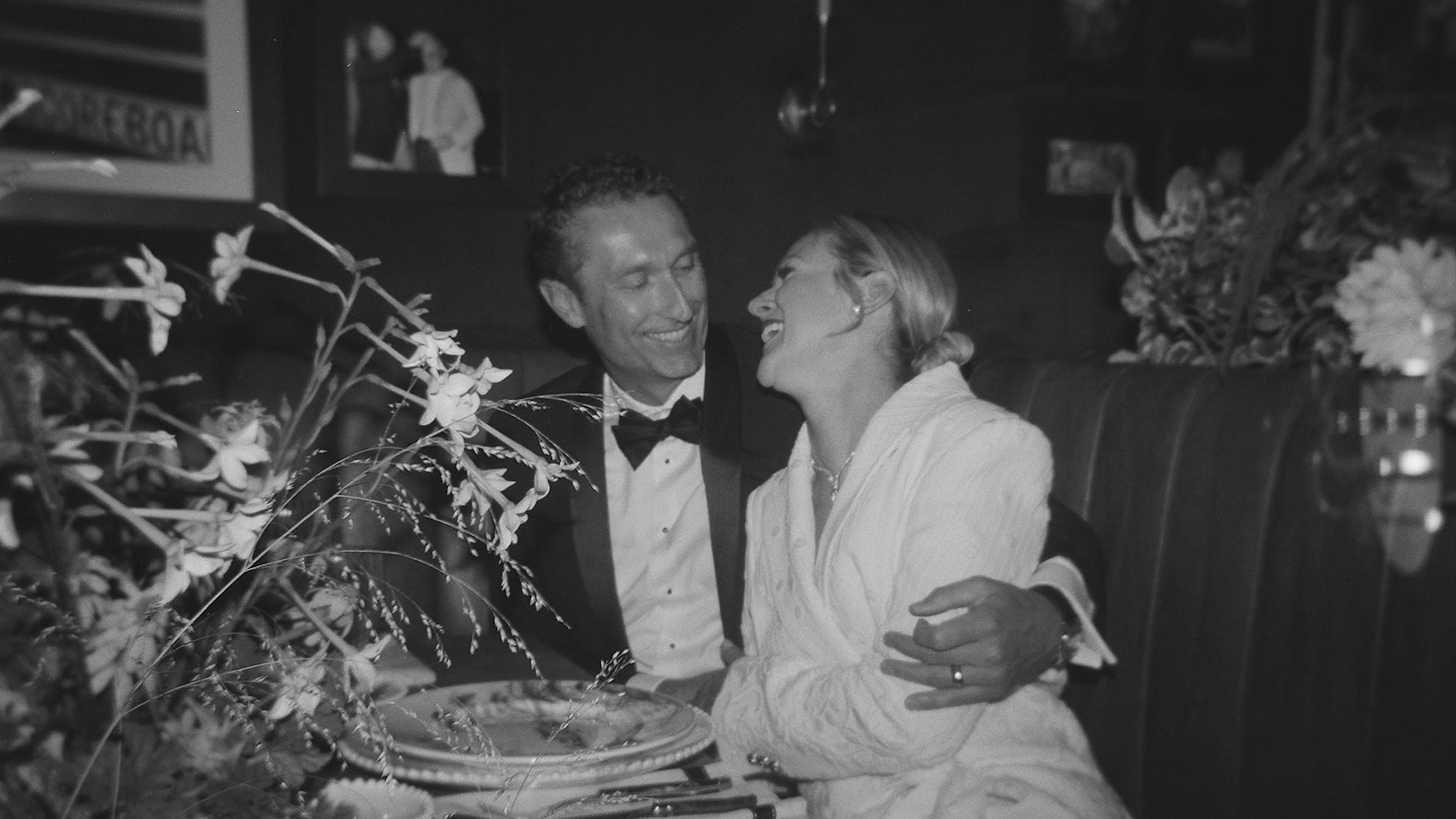 Bride and groom laughing together at intimate wedding restaurant booth