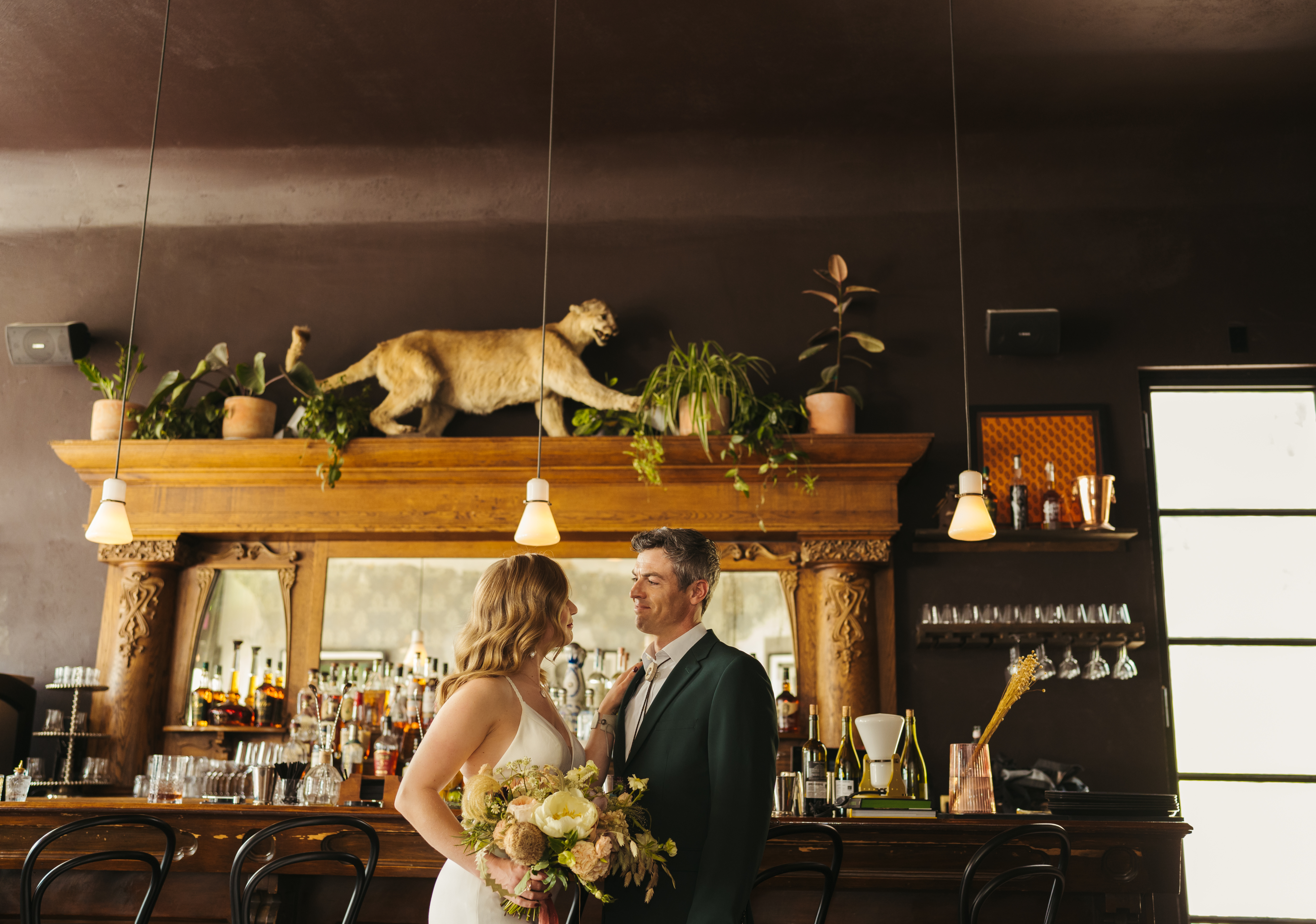 Bride wearing simple wedding dress and groom wearing charcoal grey suit at restaurant