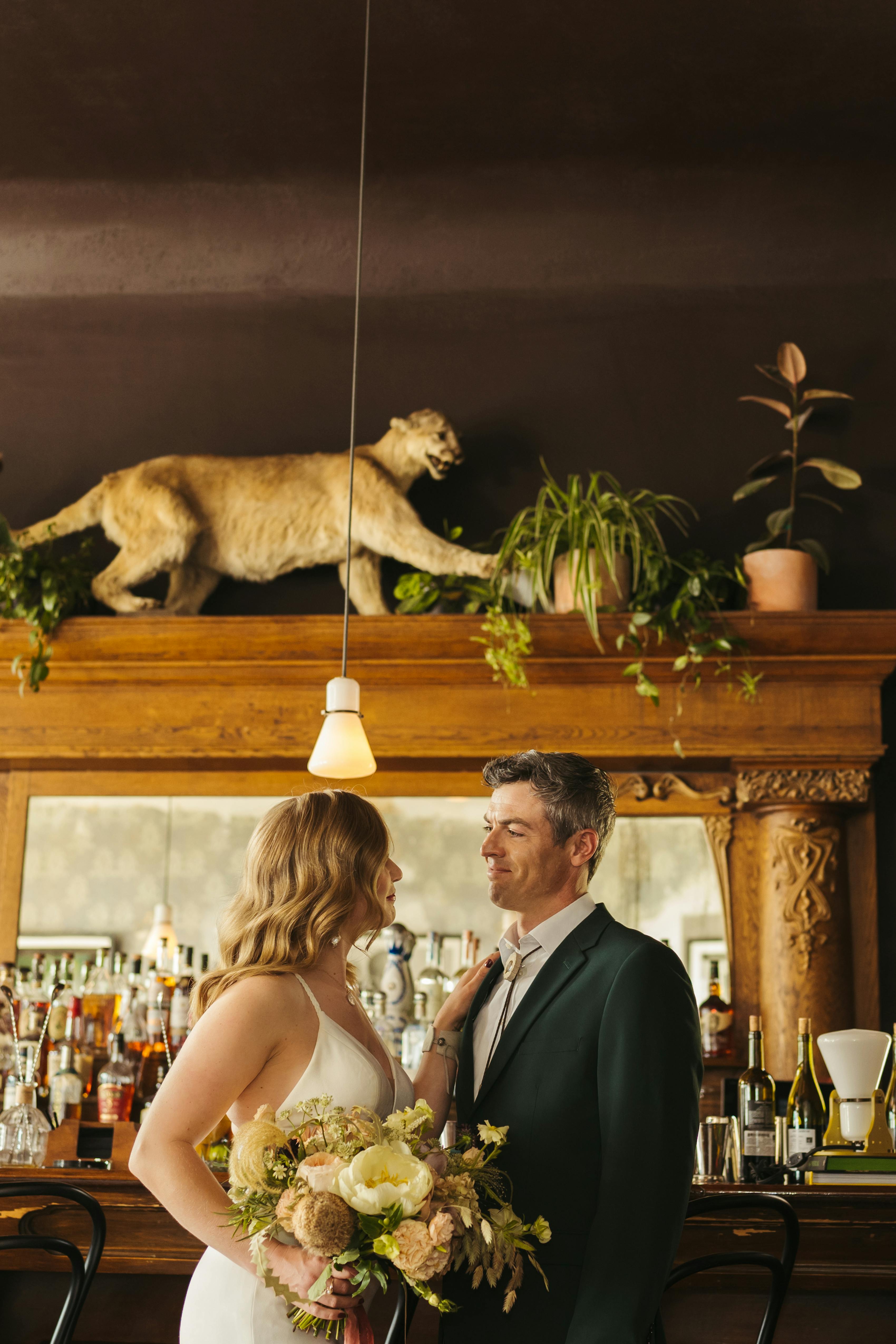 Bride wearing simple wedding dress and groom wearing charcoal grey suit at restaurant