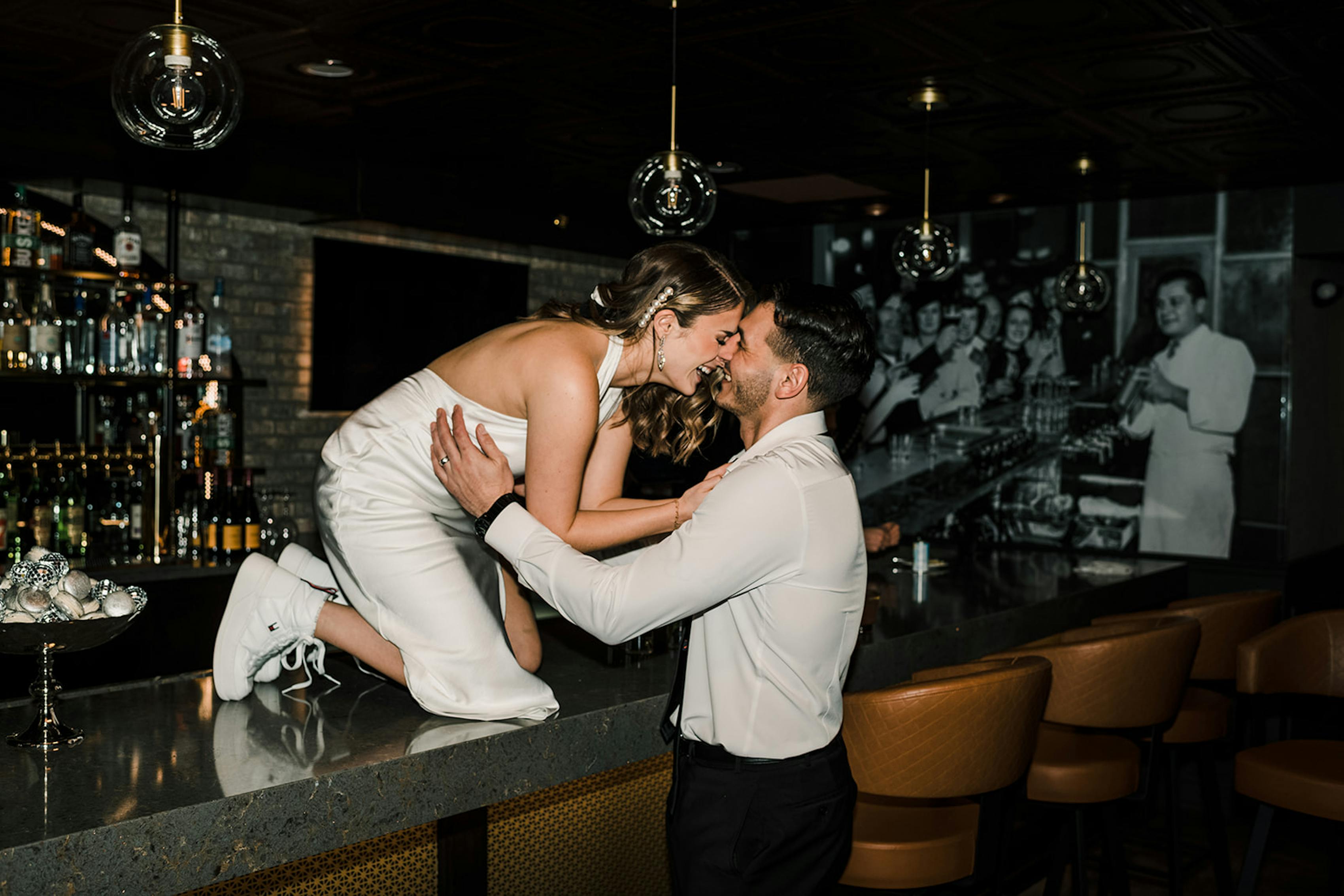Bride and groom kissing on restaurant bar with flash photography
