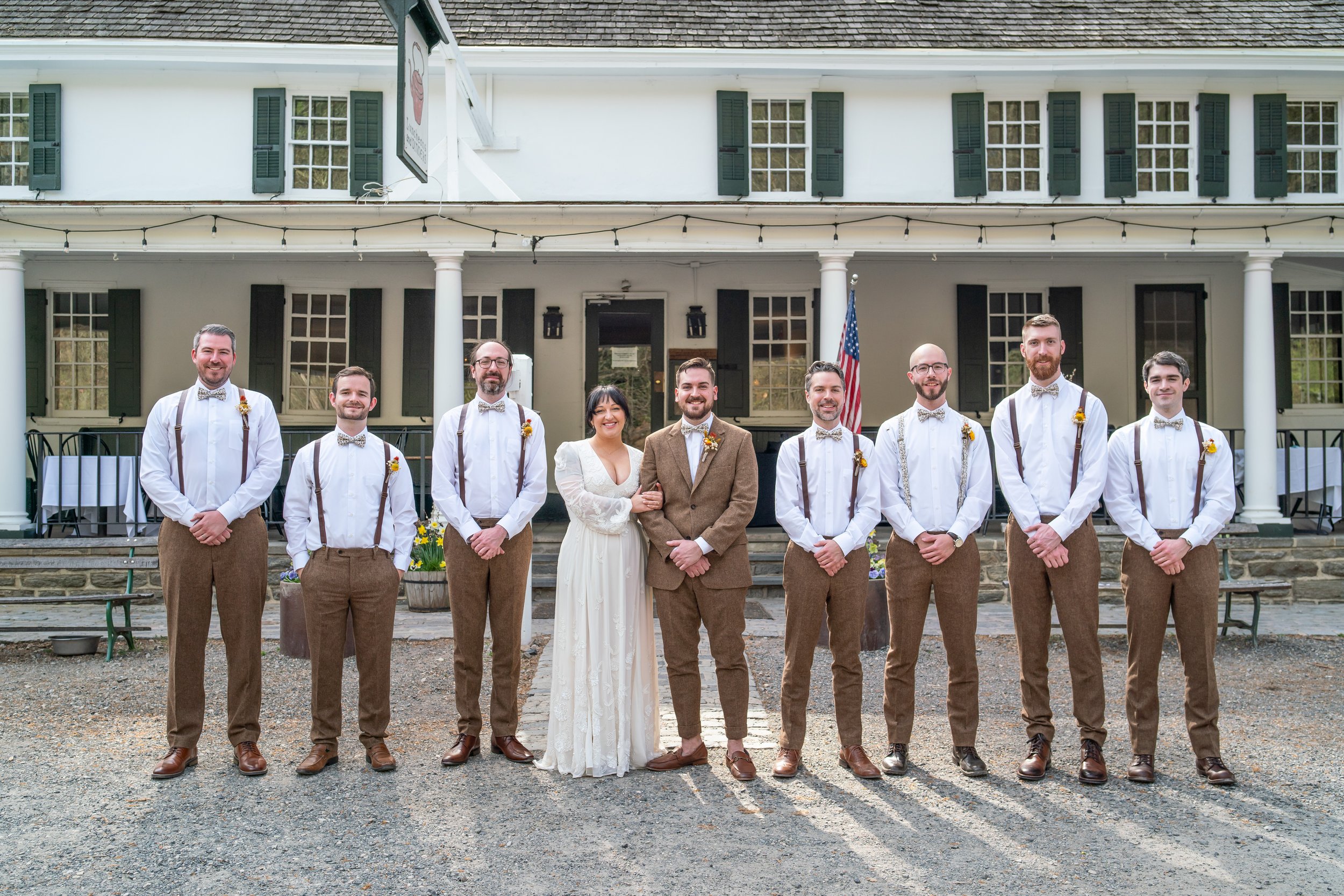 Groomsmen posing with bride and groom wearing brown tweed wedding suits