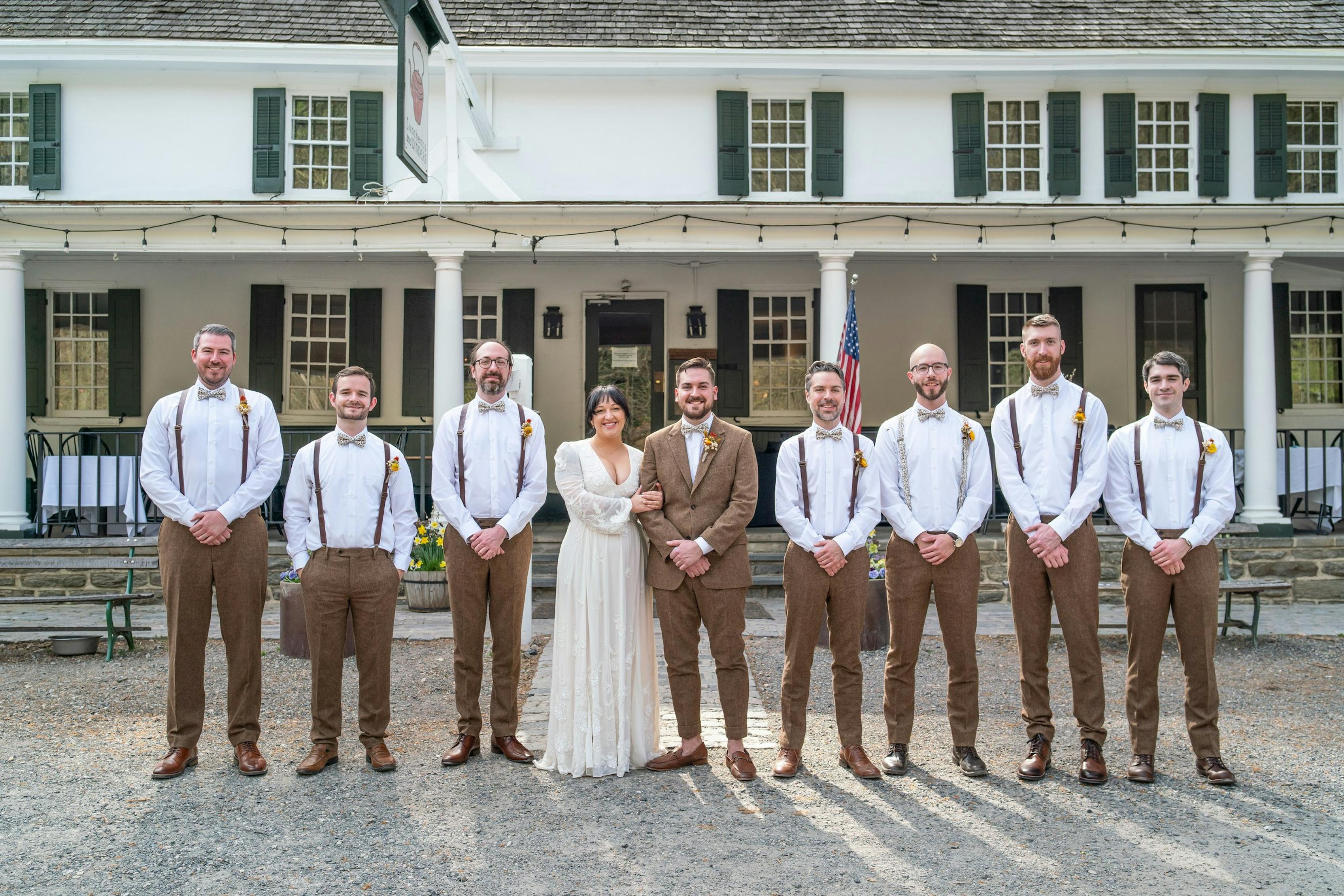 Groomsmen posing with bride and groom wearing brown tweed wedding suits