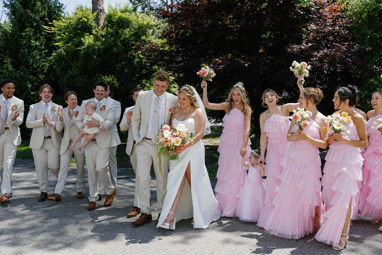 Bridal party portrait with tan groomsmen suits with light pink ruffle bridesmaid dresses