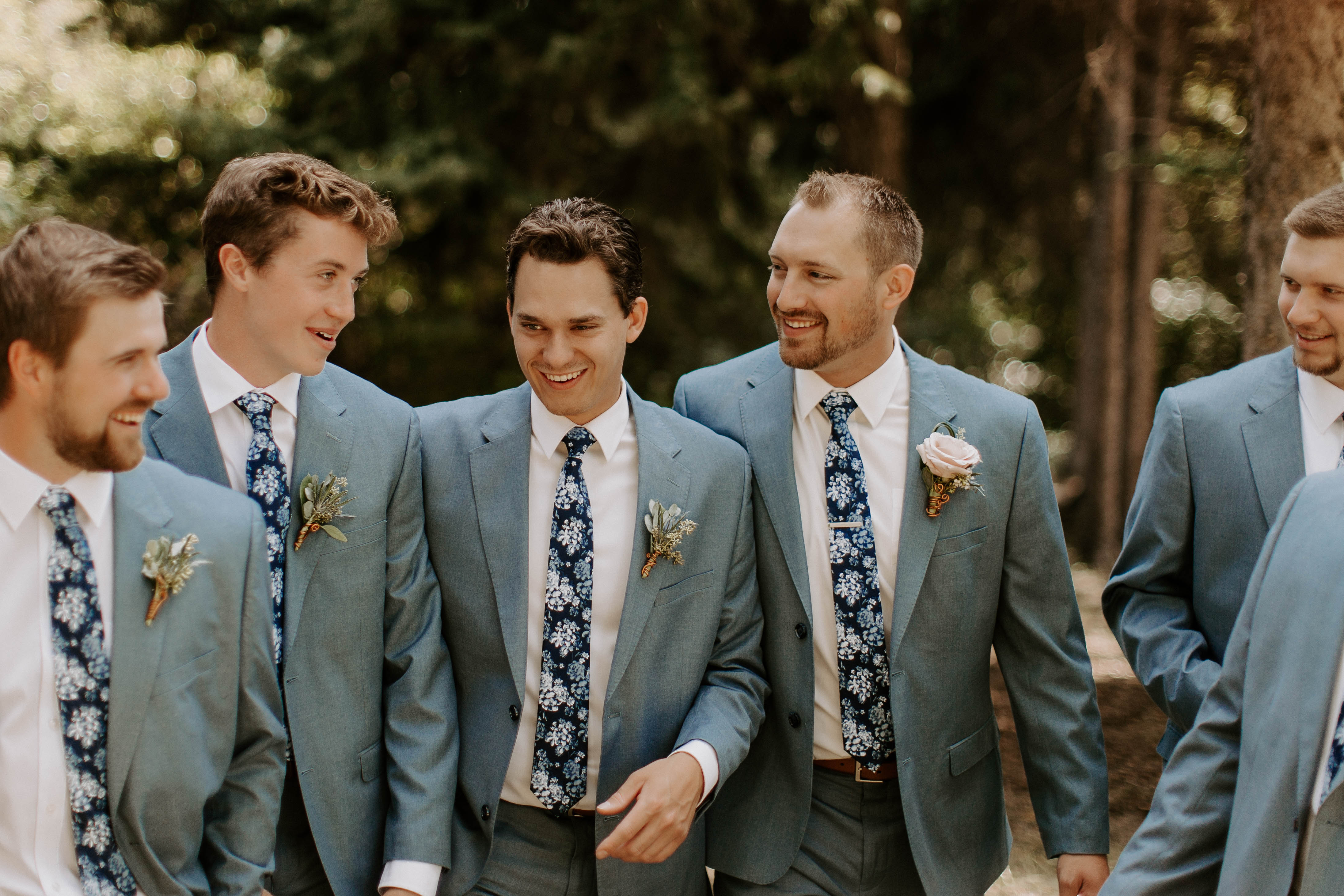 Candid groomsmen laughing wearing light blue suits with blue floral ties