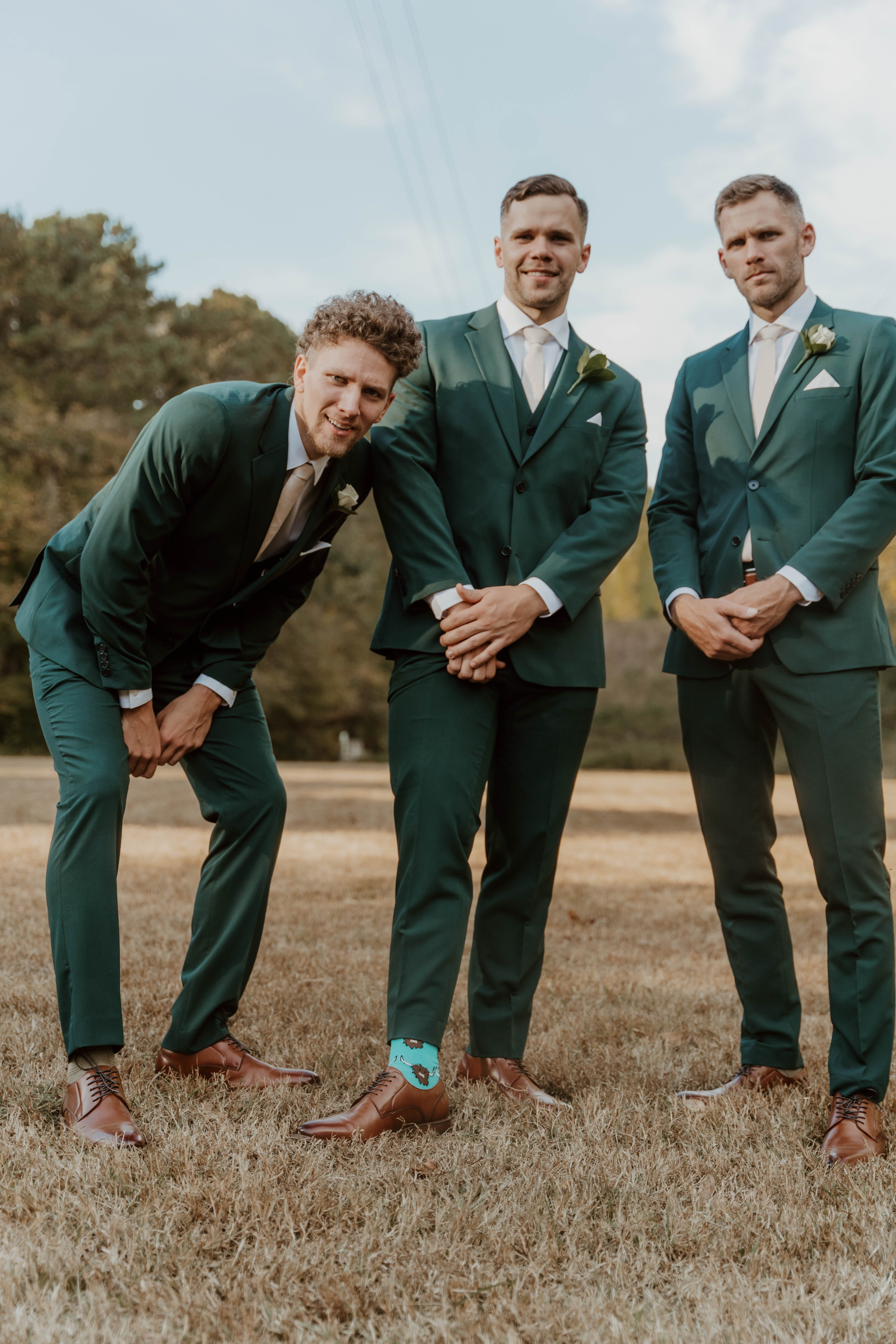 Groomsmen at outdoor wedding wearing dark forest green suits