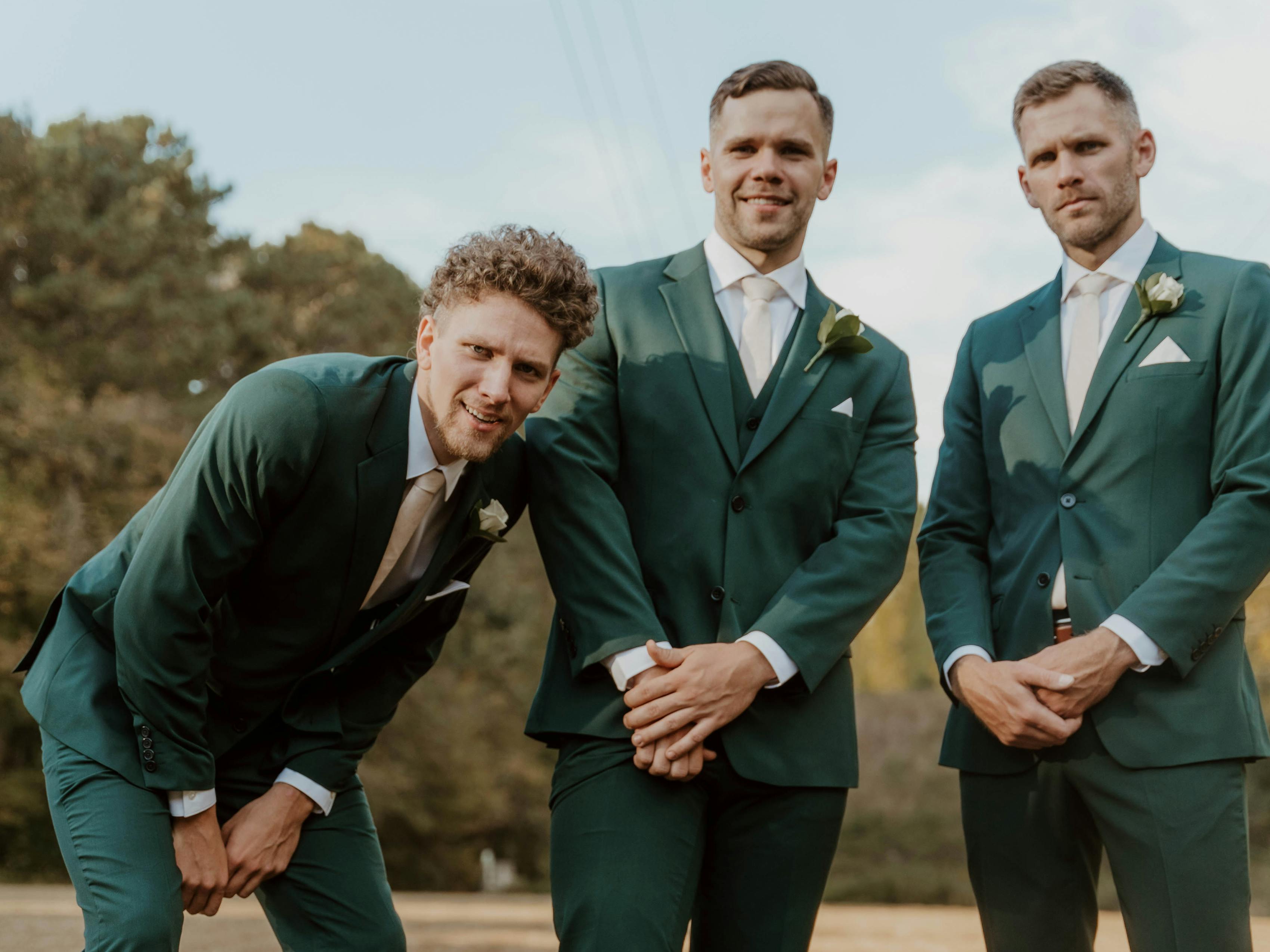 Groomsmen at outdoor wedding wearing dark forest green suits