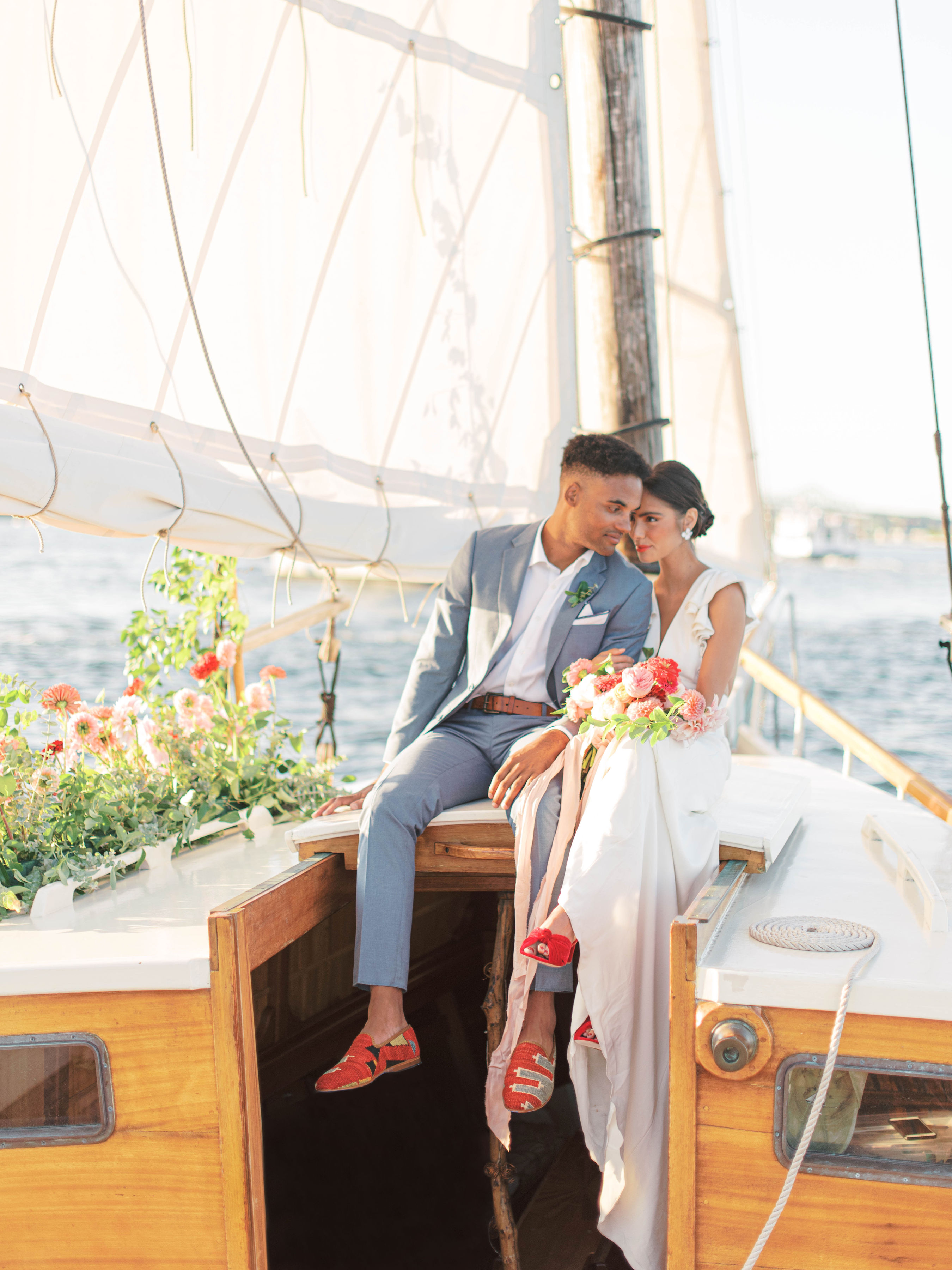 Groom wearing light blue suit without tie on sailboat for beach destination wedding