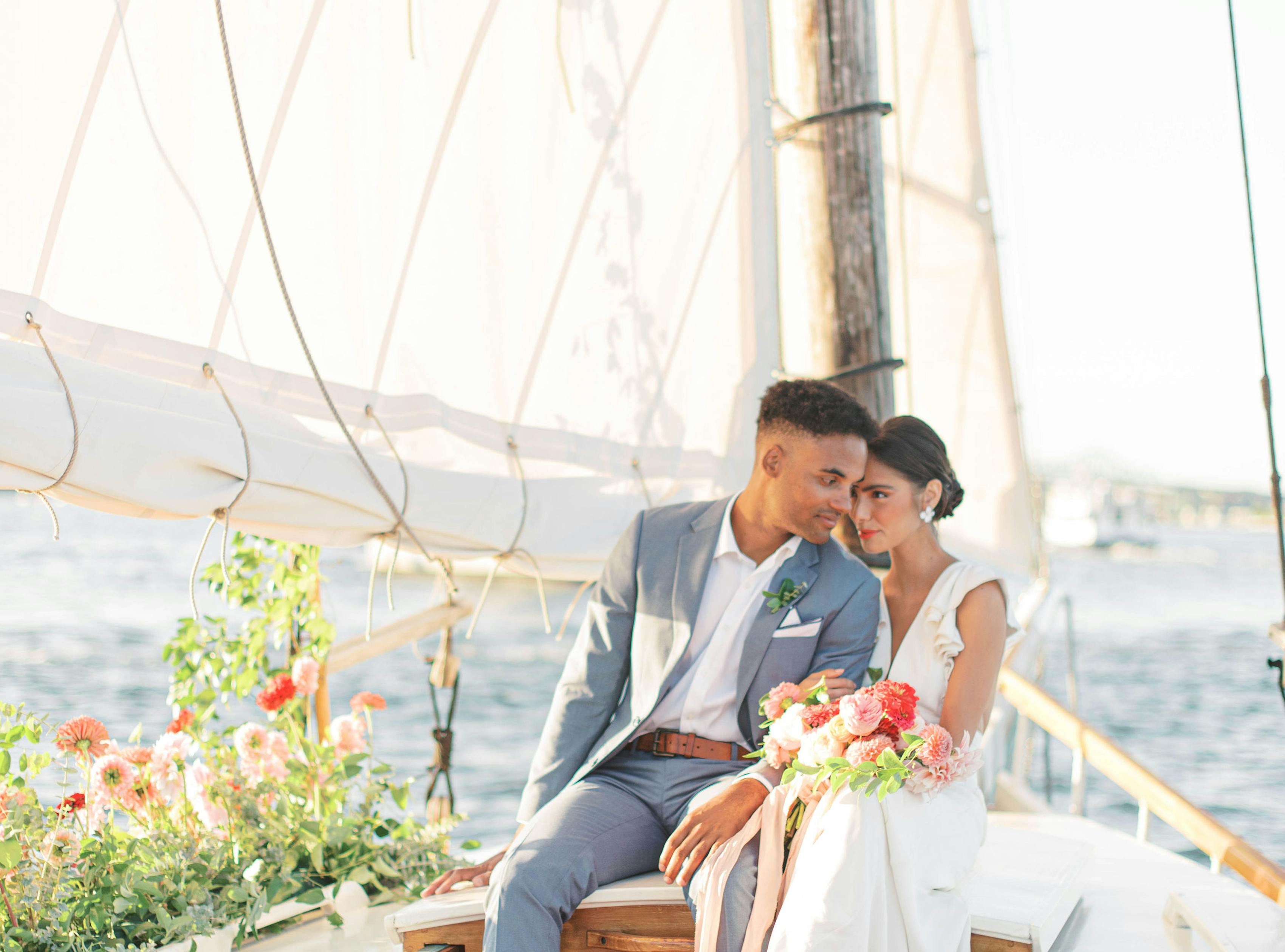 Groom wearing light blue suit without tie on sailboat for beach destination wedding