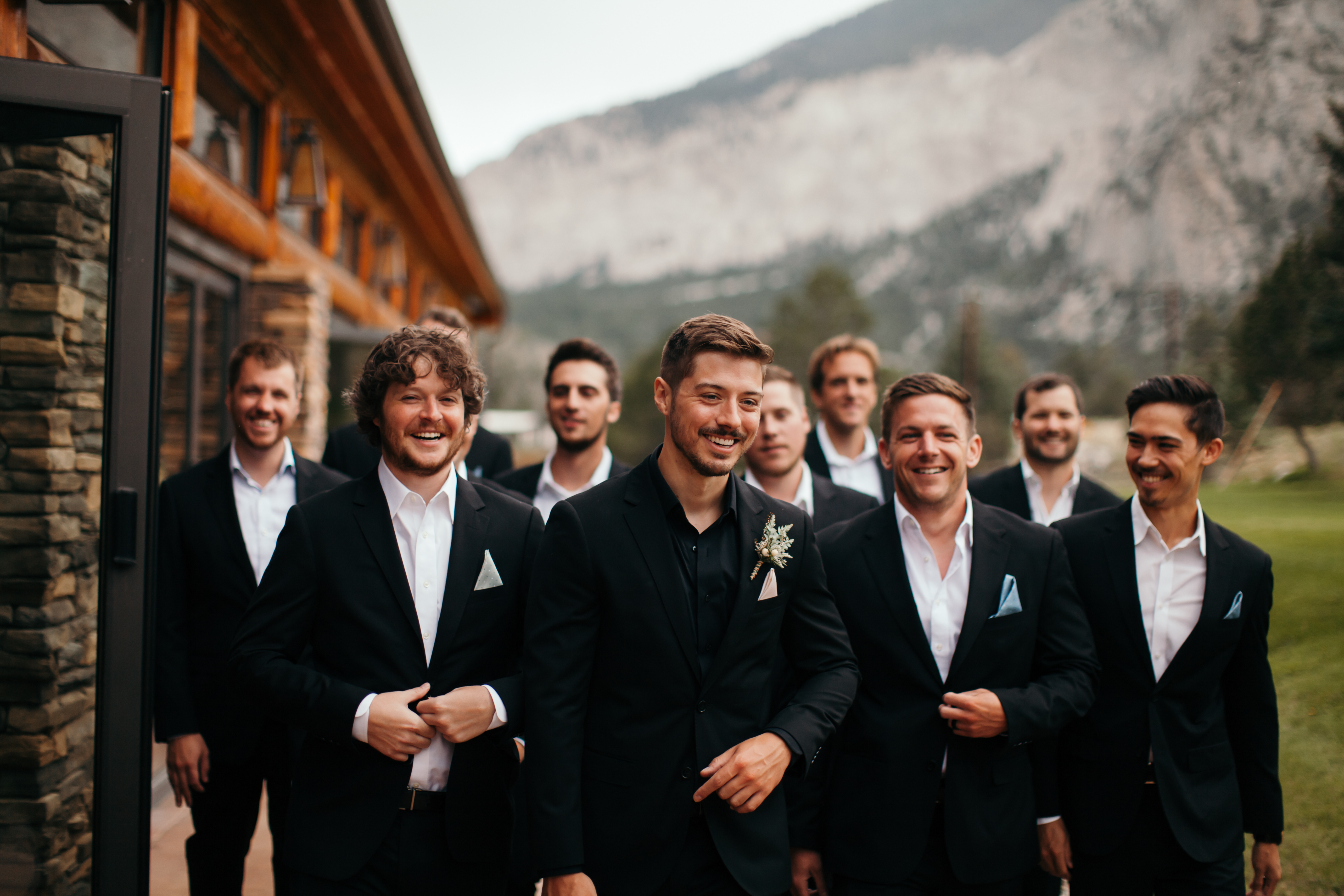 Groomsmen in black suits without ties and groom wearing all-black dress shirt at mountain wedding