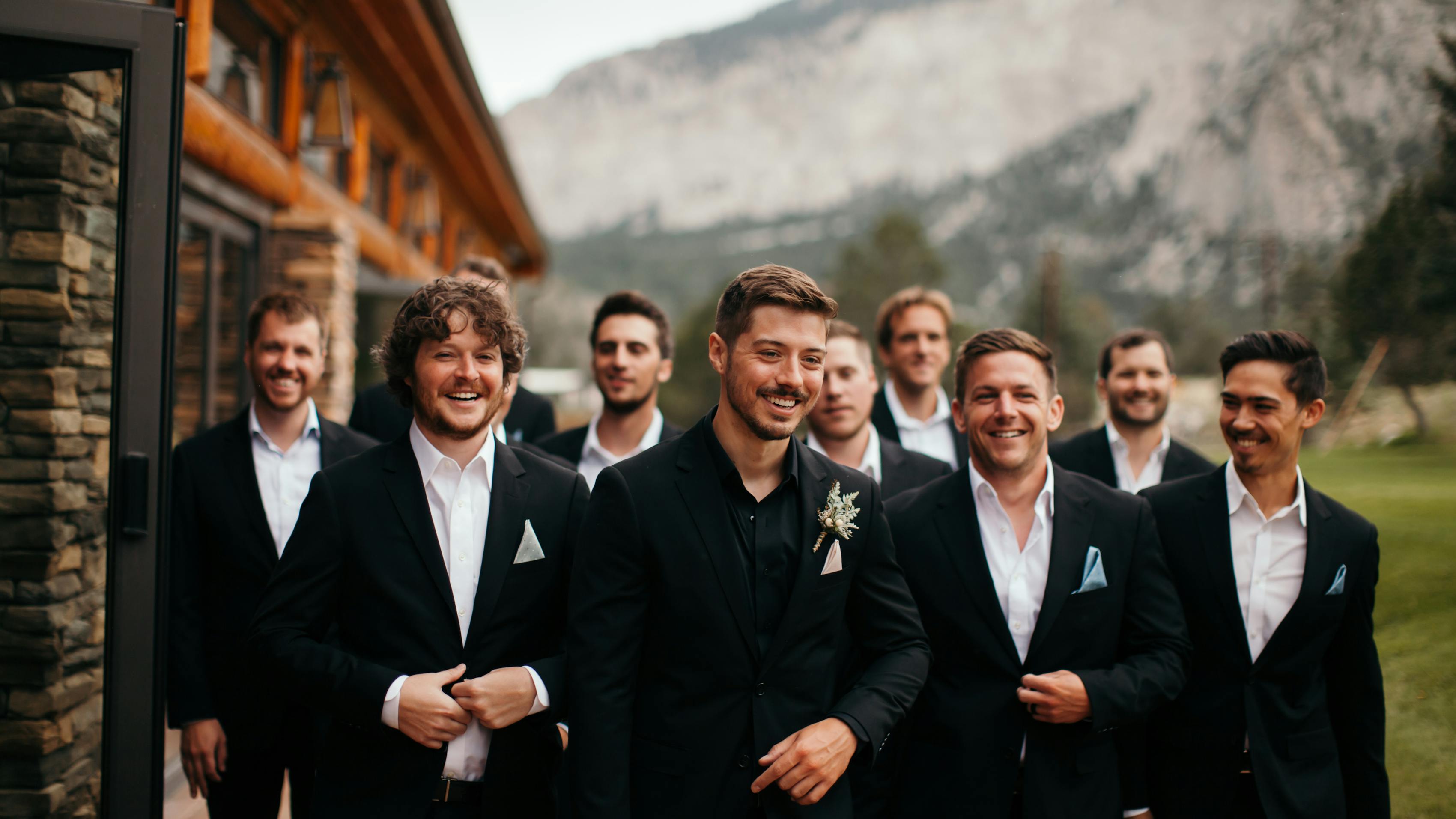 Groomsmen in black suits without ties and groom wearing all-black dress shirt at mountain wedding