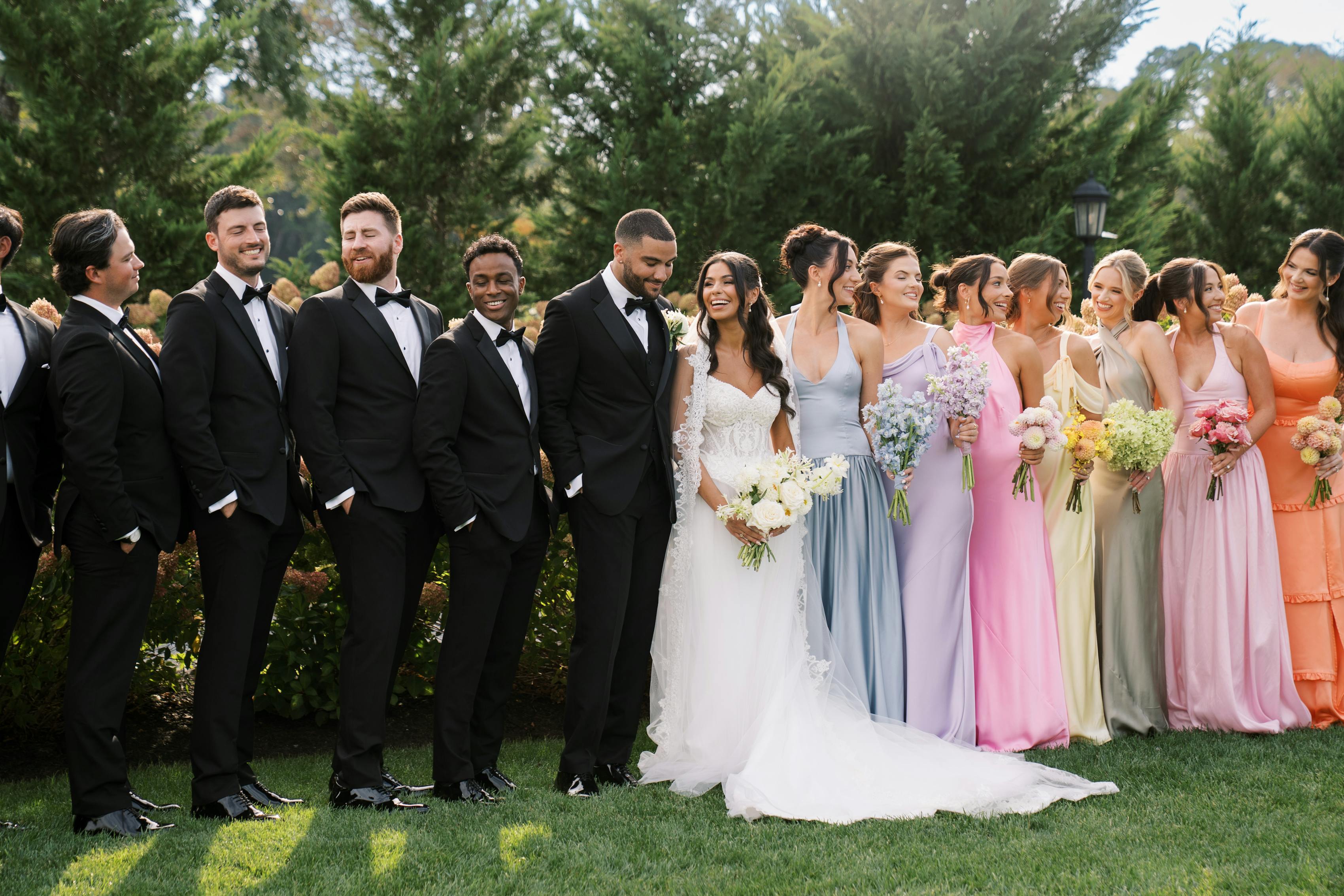 Colorful black tie wedding party with mix and match pastel bridesmaid dresses and black groomsmen tuxedos