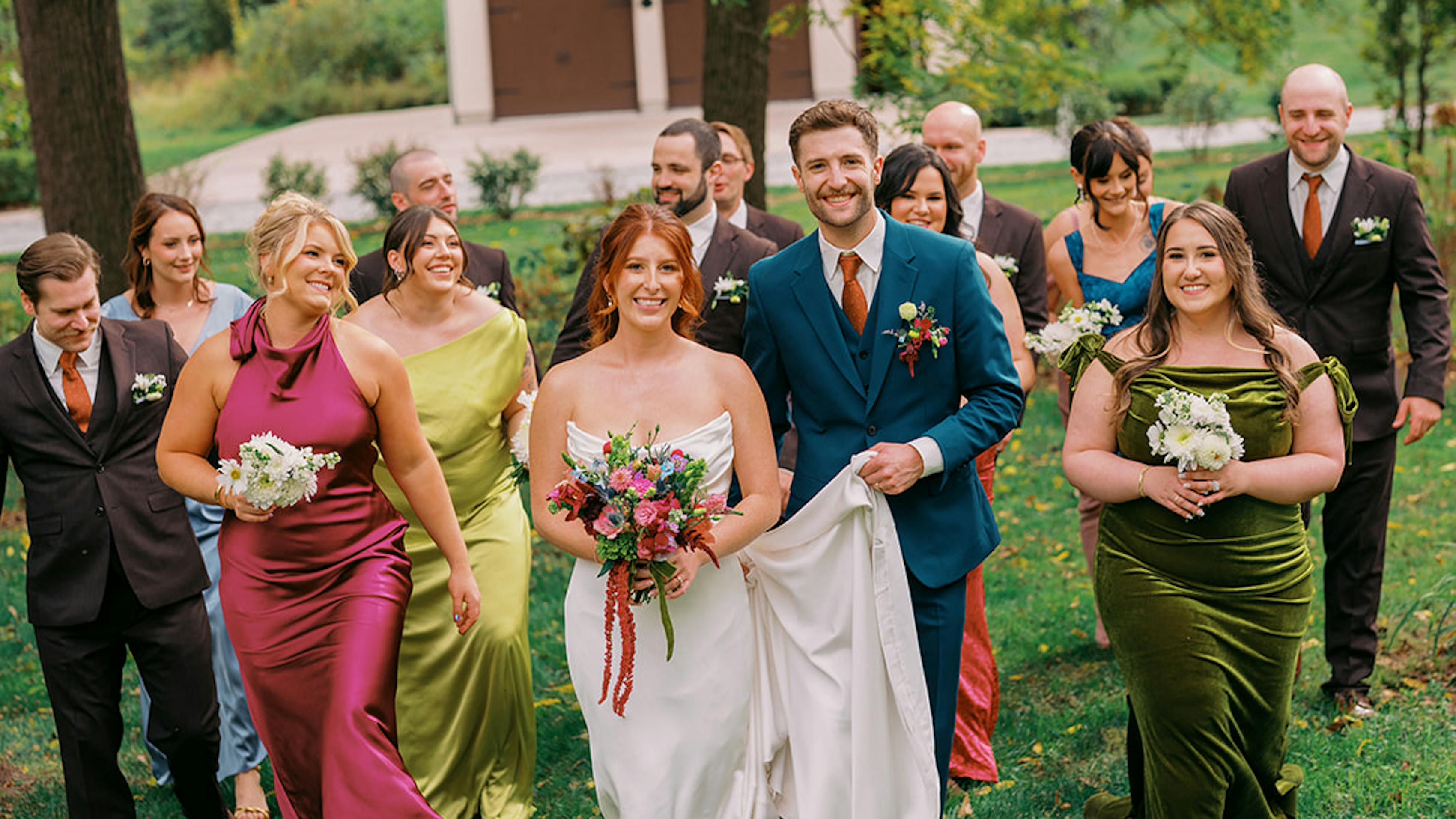 Mix and match wedding party with teal groom suit, brown groomsmen suit, and bright earth tone bridesmaid dresses