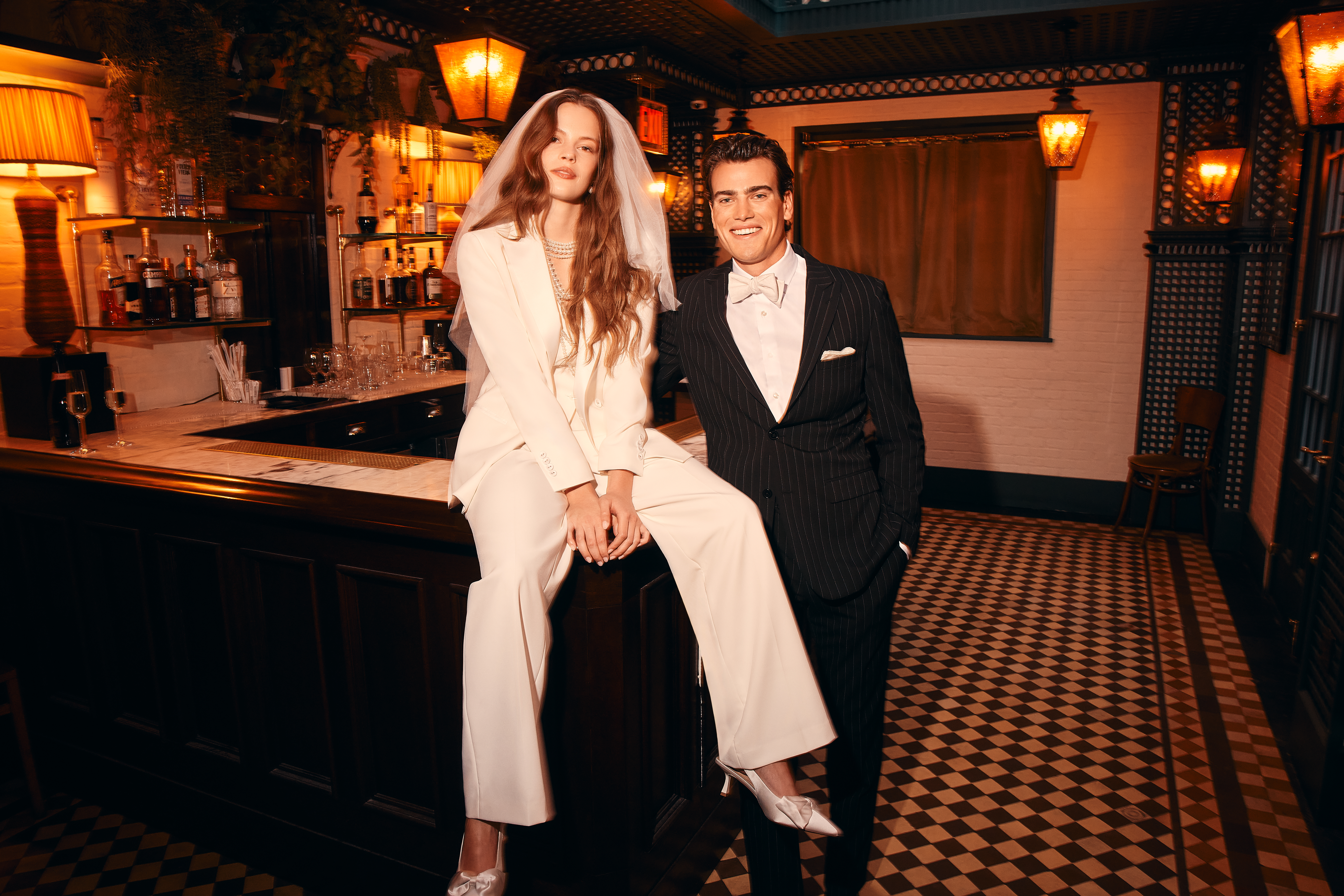 Newlyweds wearing wide leg bridal suit a groom wearing black suit at restaurant wedding venue