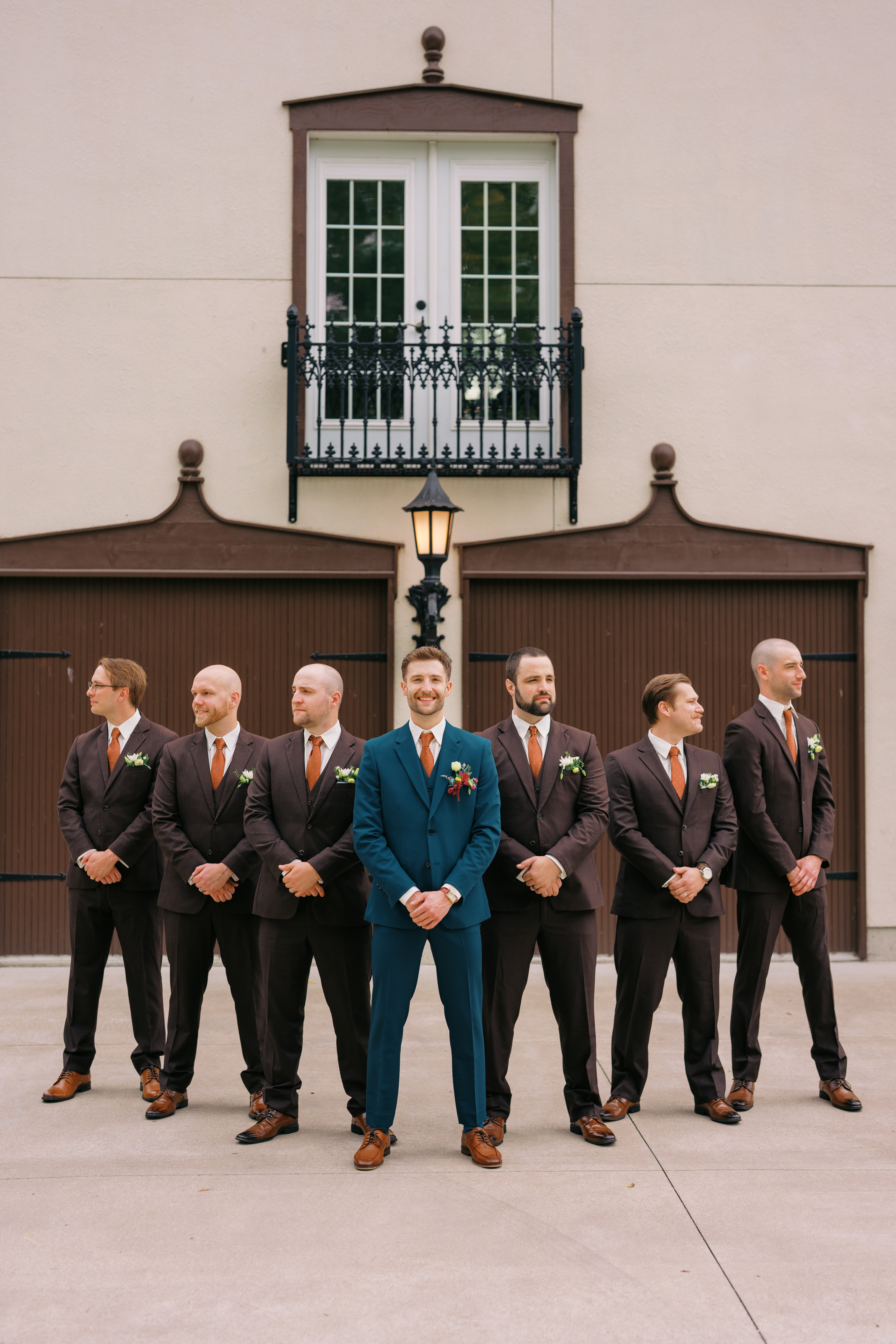 Groom wearing teal suit with groomsmen wearing dark brown suits and rust ties