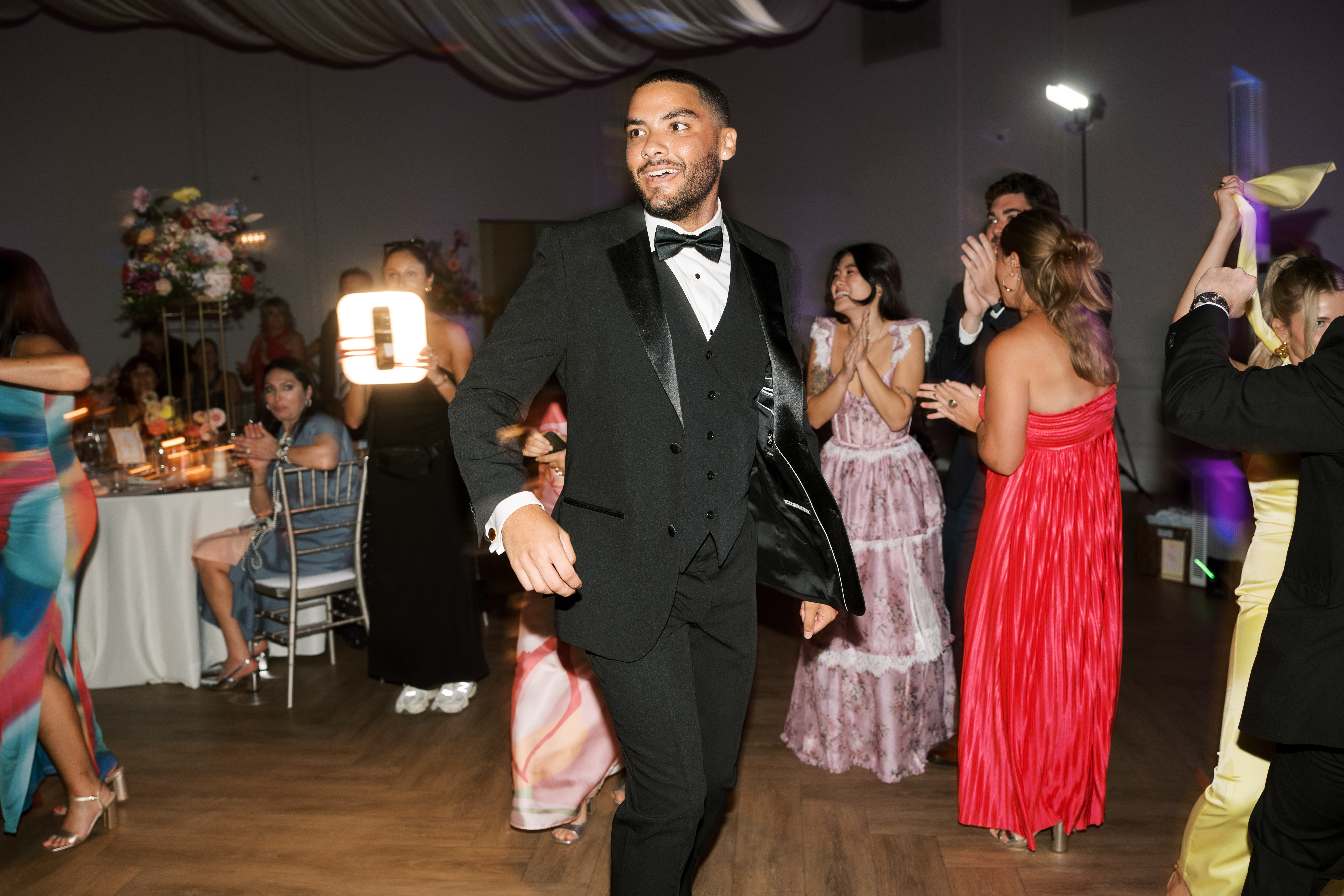 Man wearing black tuxedo as wedding guest outfit dancing at black-tie reception
