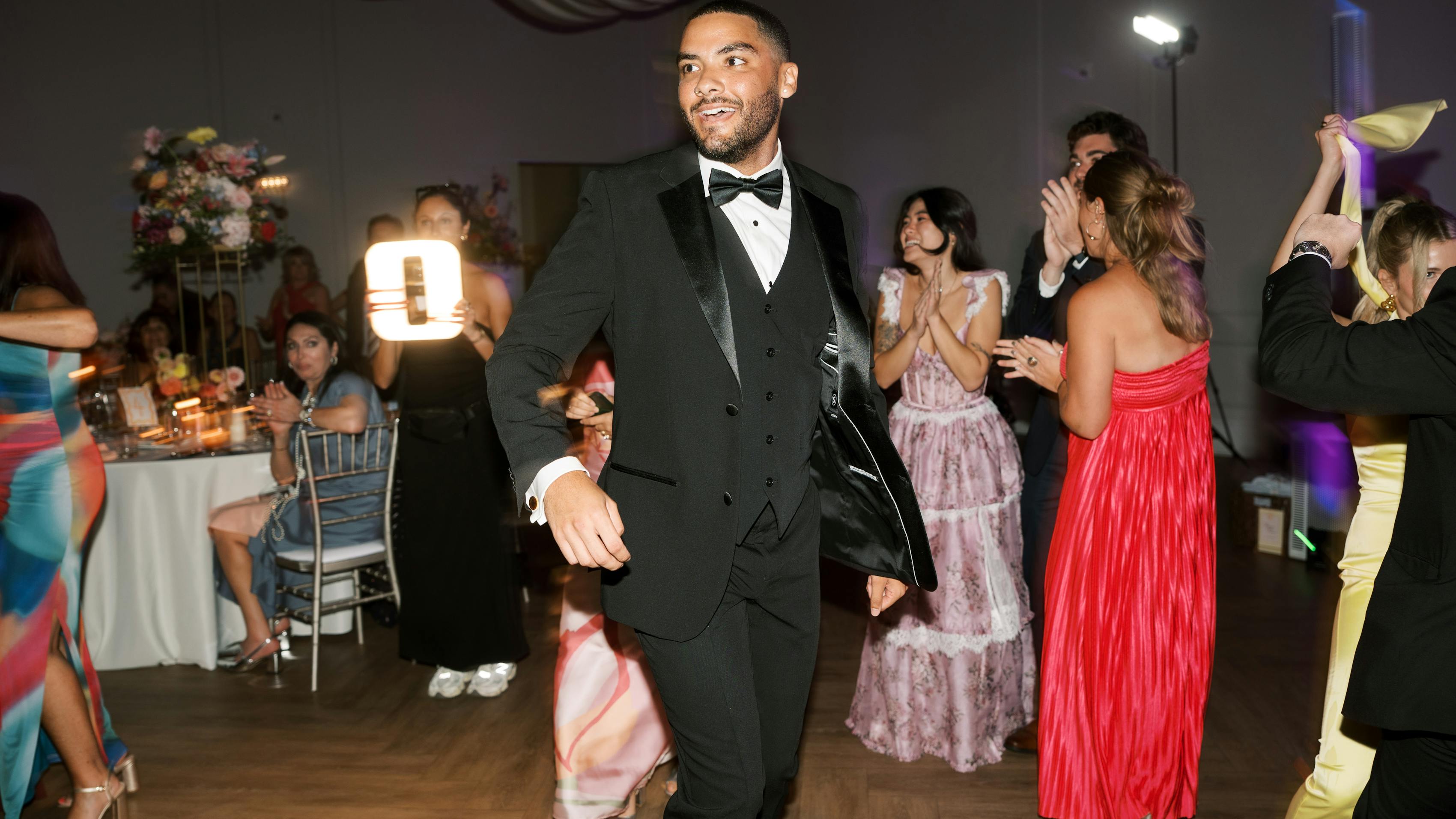 Man wearing black tuxedo as wedding guest outfit dancing at black-tie reception