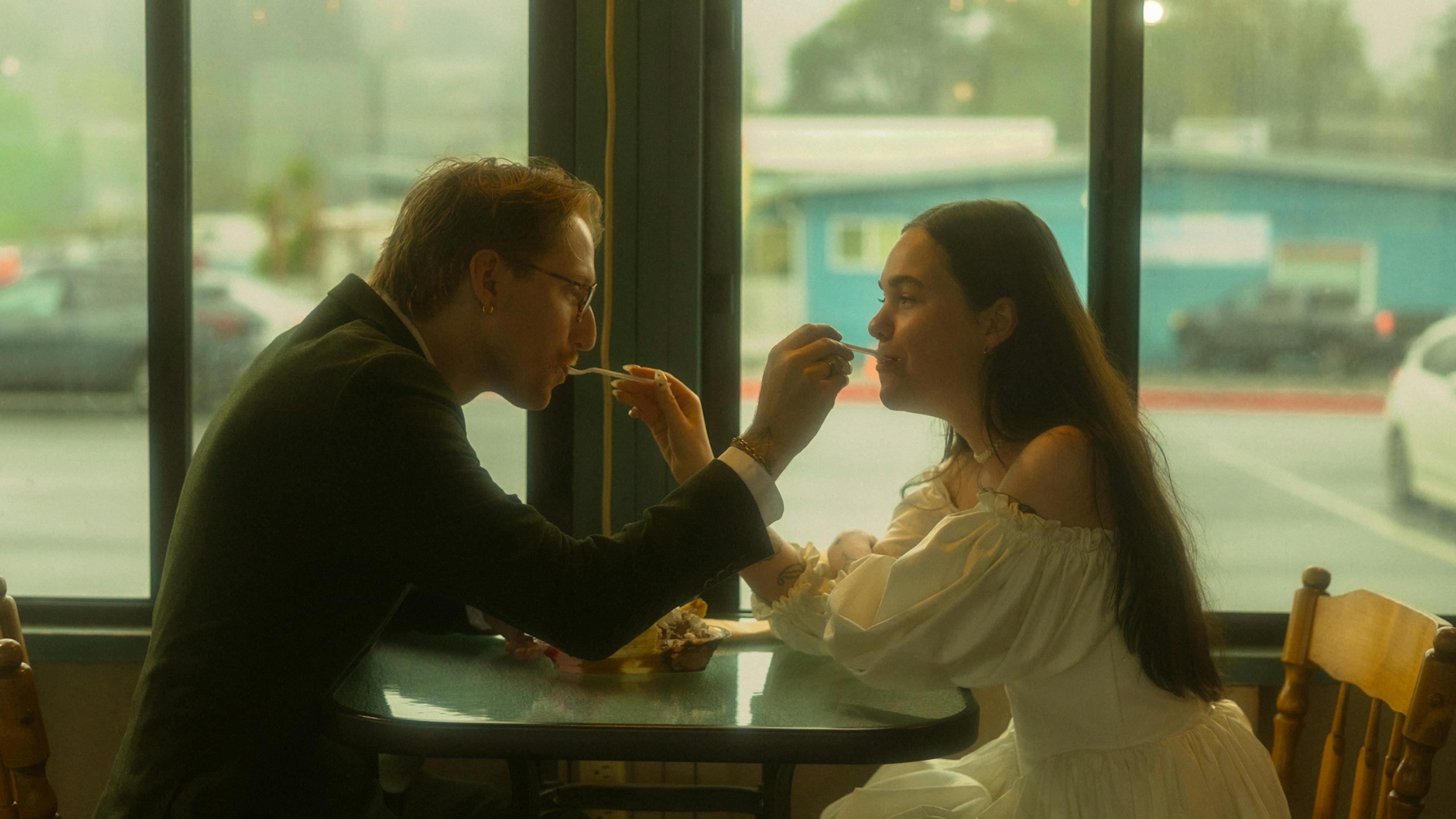 Dressed up couple wearing suit and gown in country diner feeding each other french fries