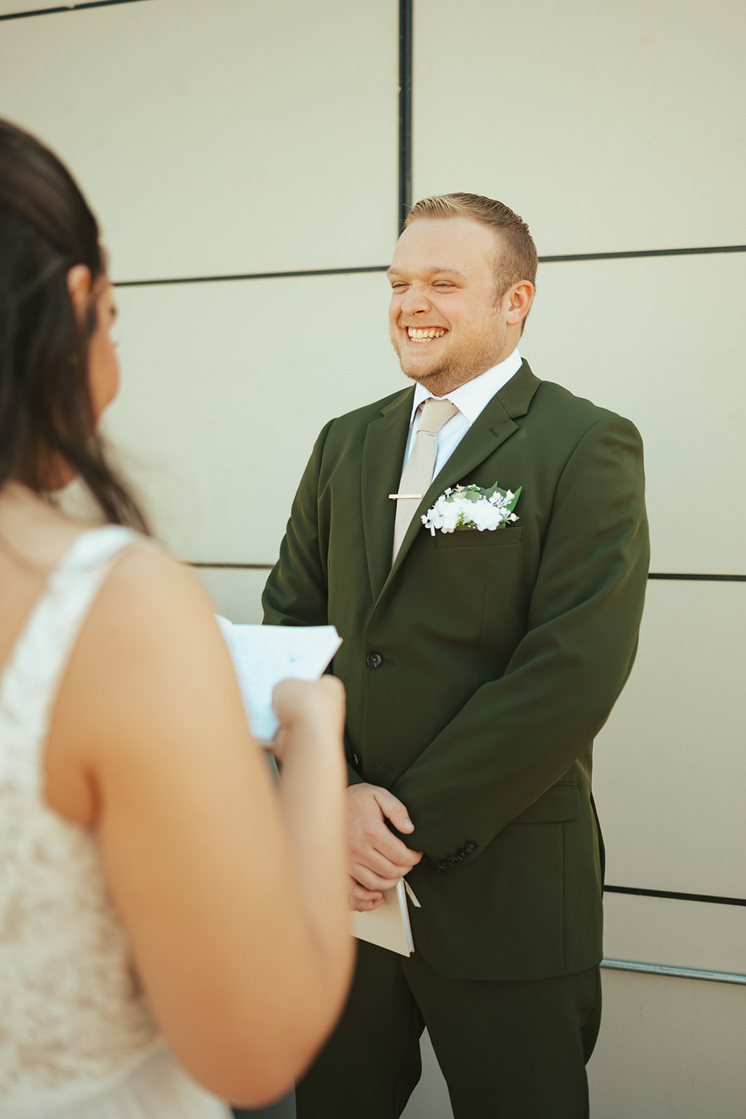 Groom wearing olive green wedding suit smiling during civil ceremony
