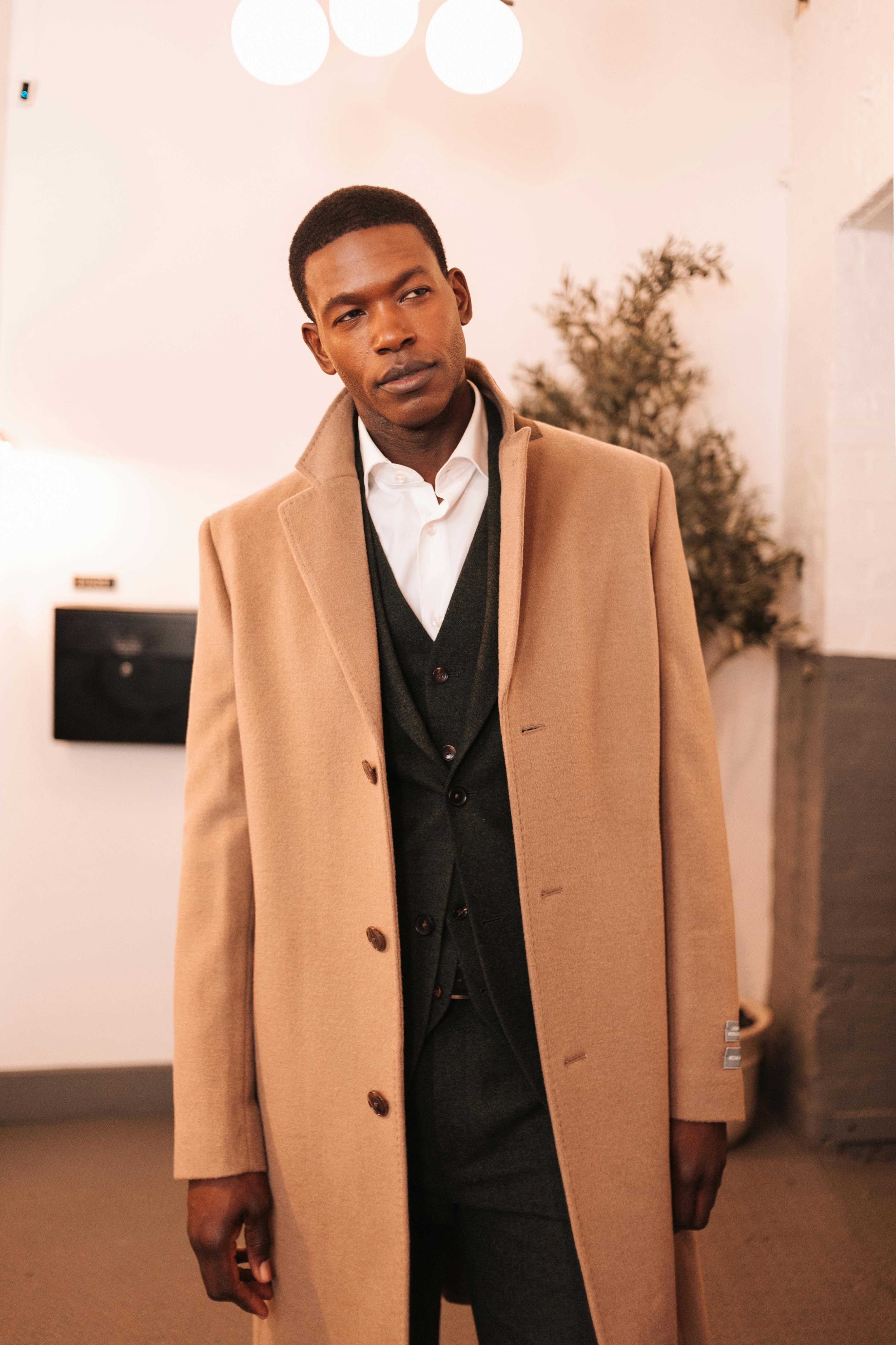 Groom dressed for casual winter wedding in green tweed suit with long wool overcoat