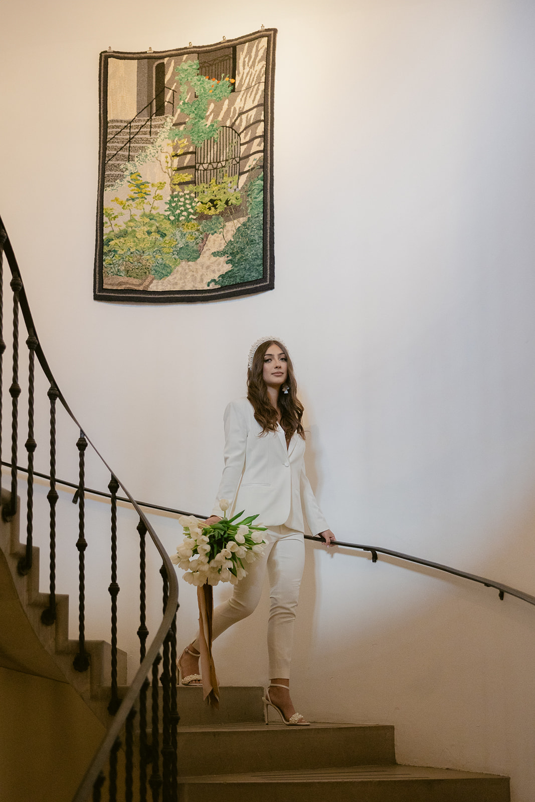 Bride wearing women's white suit walking up stairs at city hall elopement