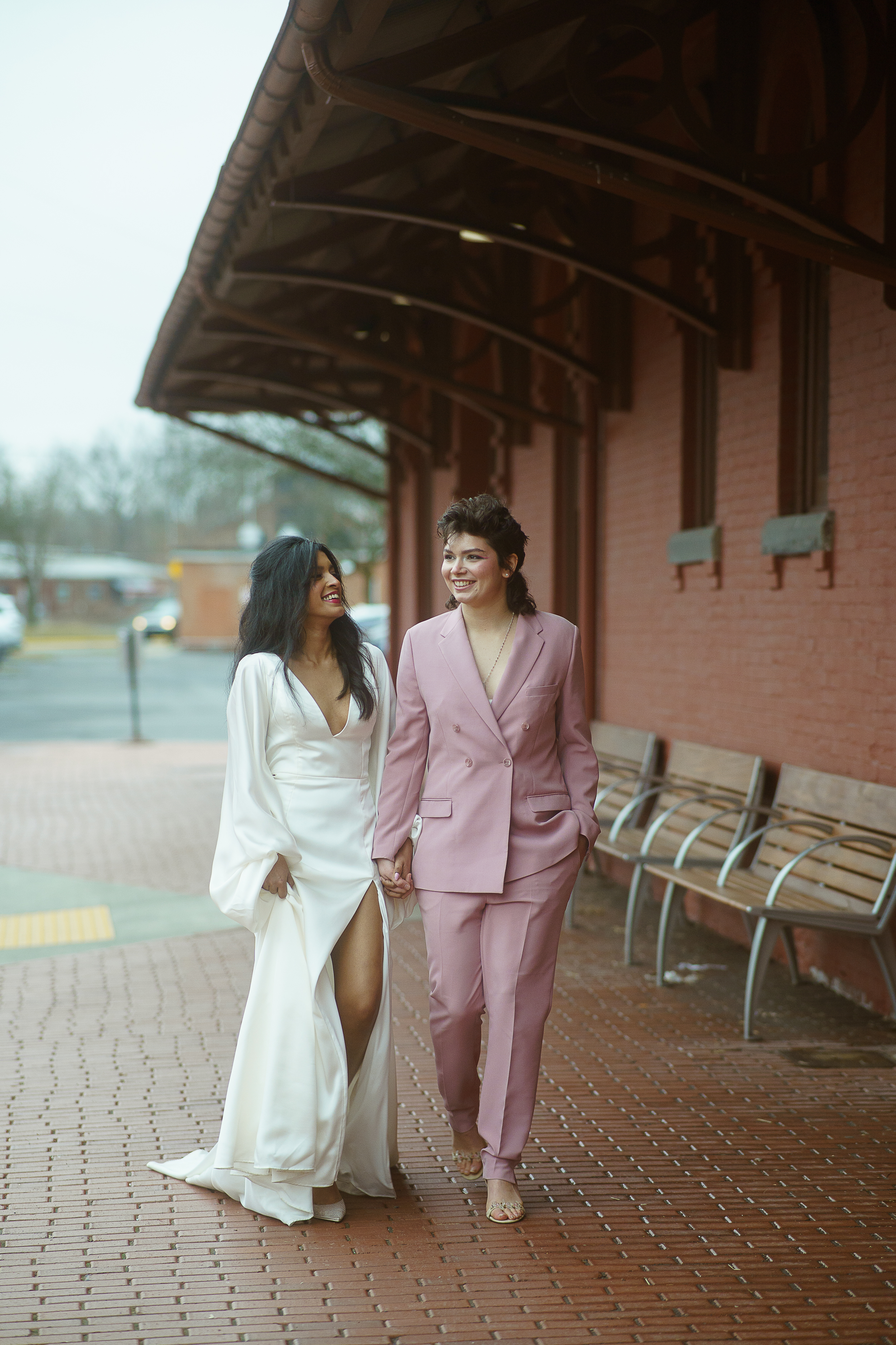 Brides at lesbian courthouse wedding wearing simple v-neck gown and pink women's suit 