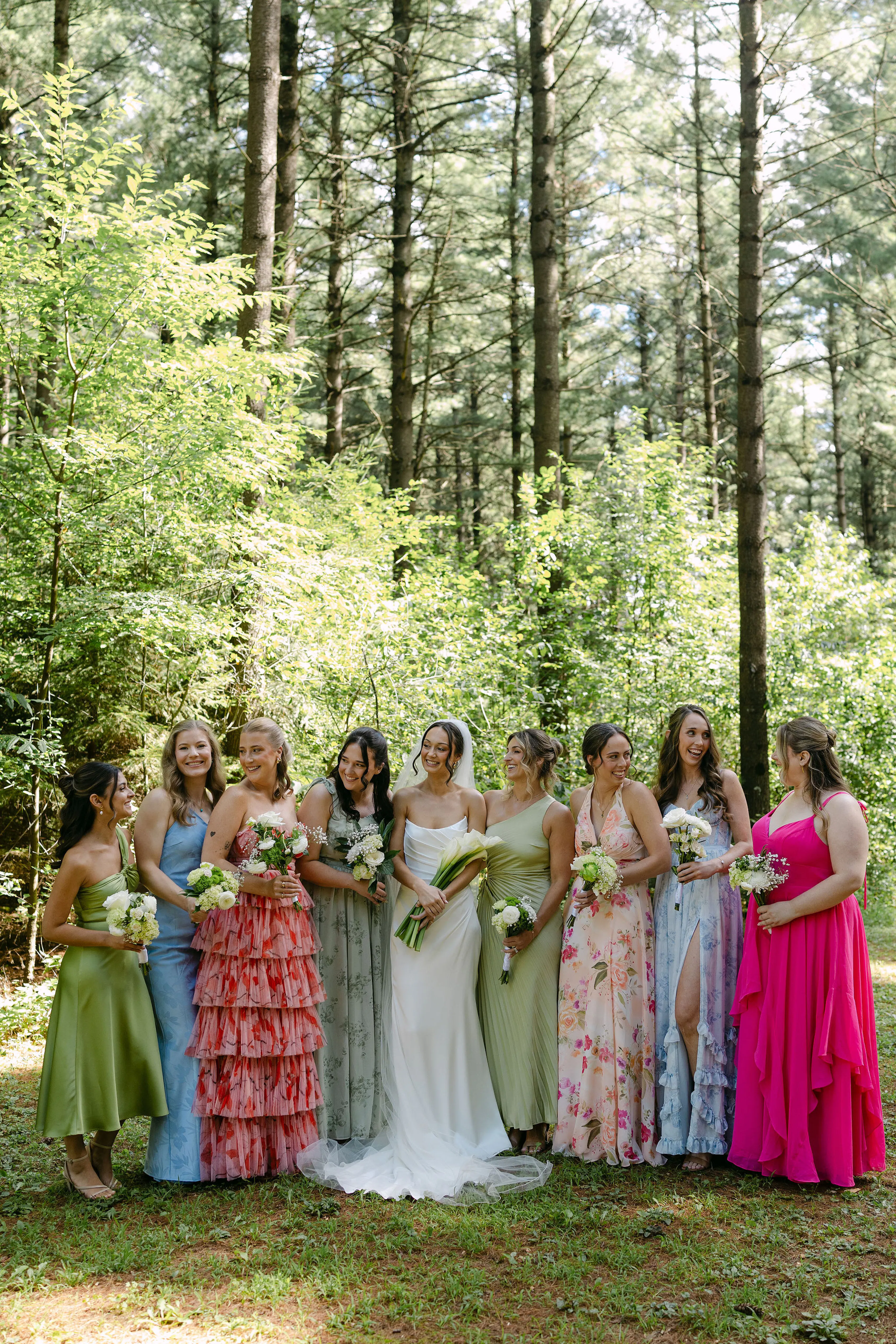 Bride and bidesmaids wearing mismatched dresses in green, blue, and pink for summer wedding